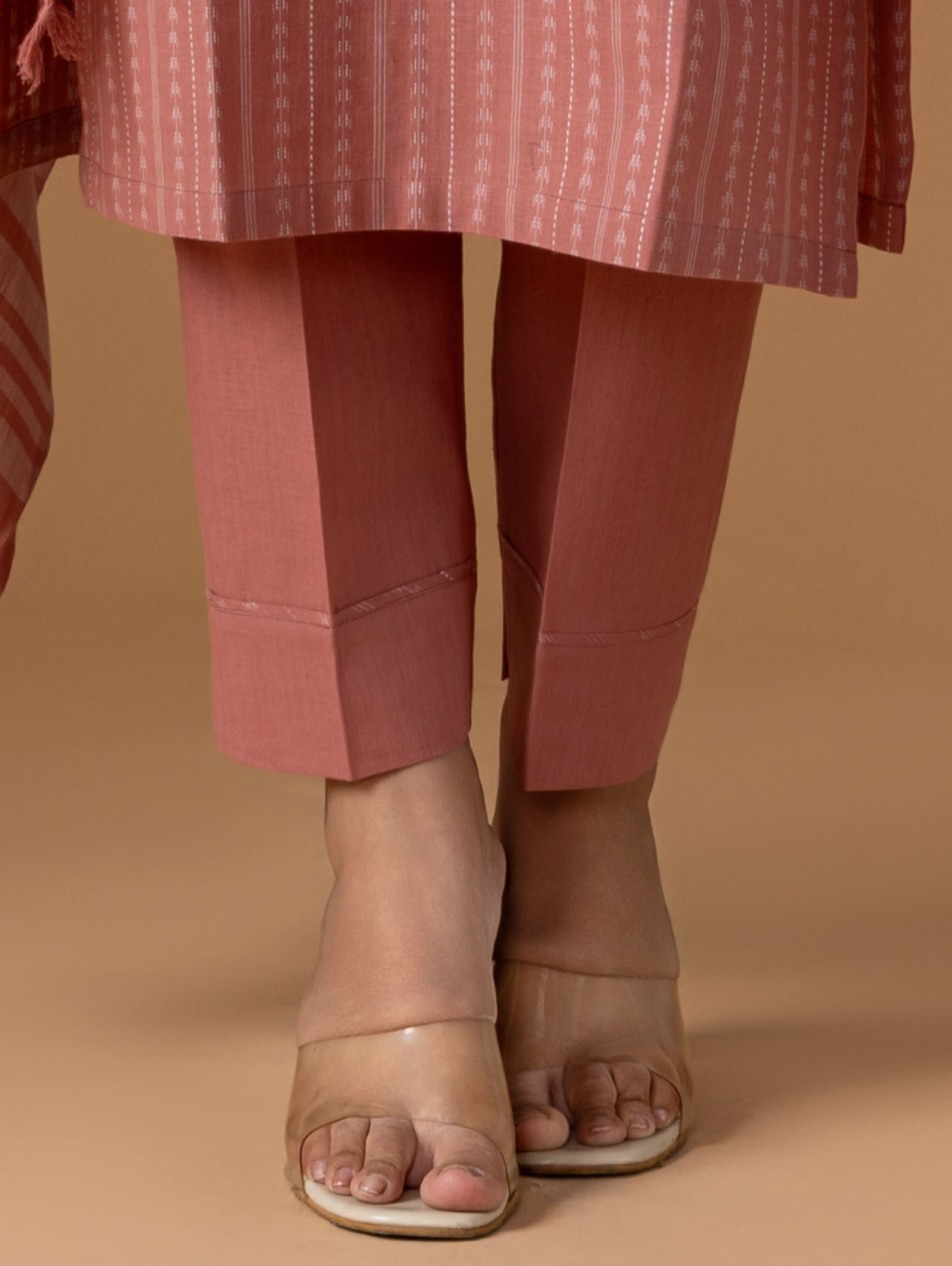 Person wearing pink pants and a matching top on a beige background