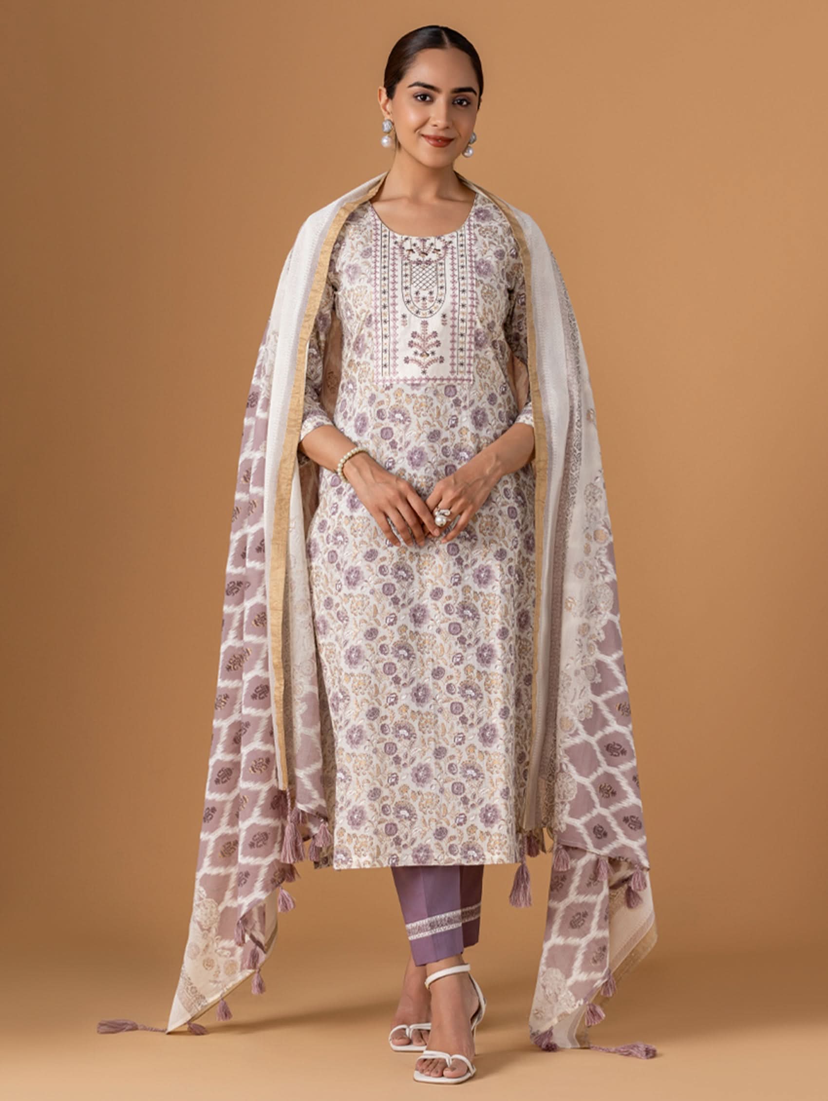 Woman wearing a floral kurta with a matching dupatta on a beige background