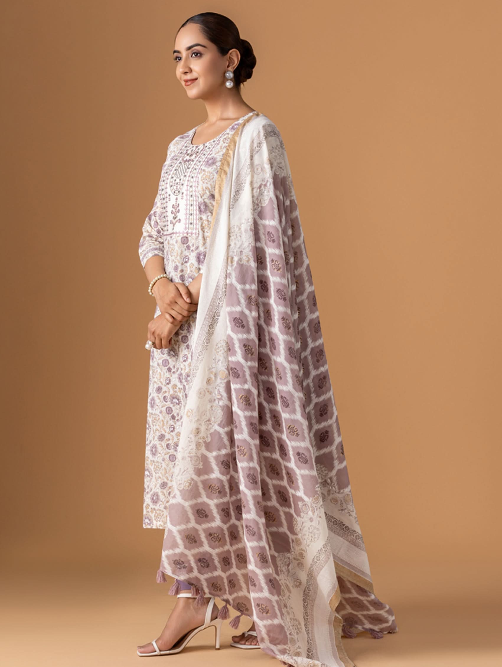 Woman wearing a white and brown patterned outfit on a beige background