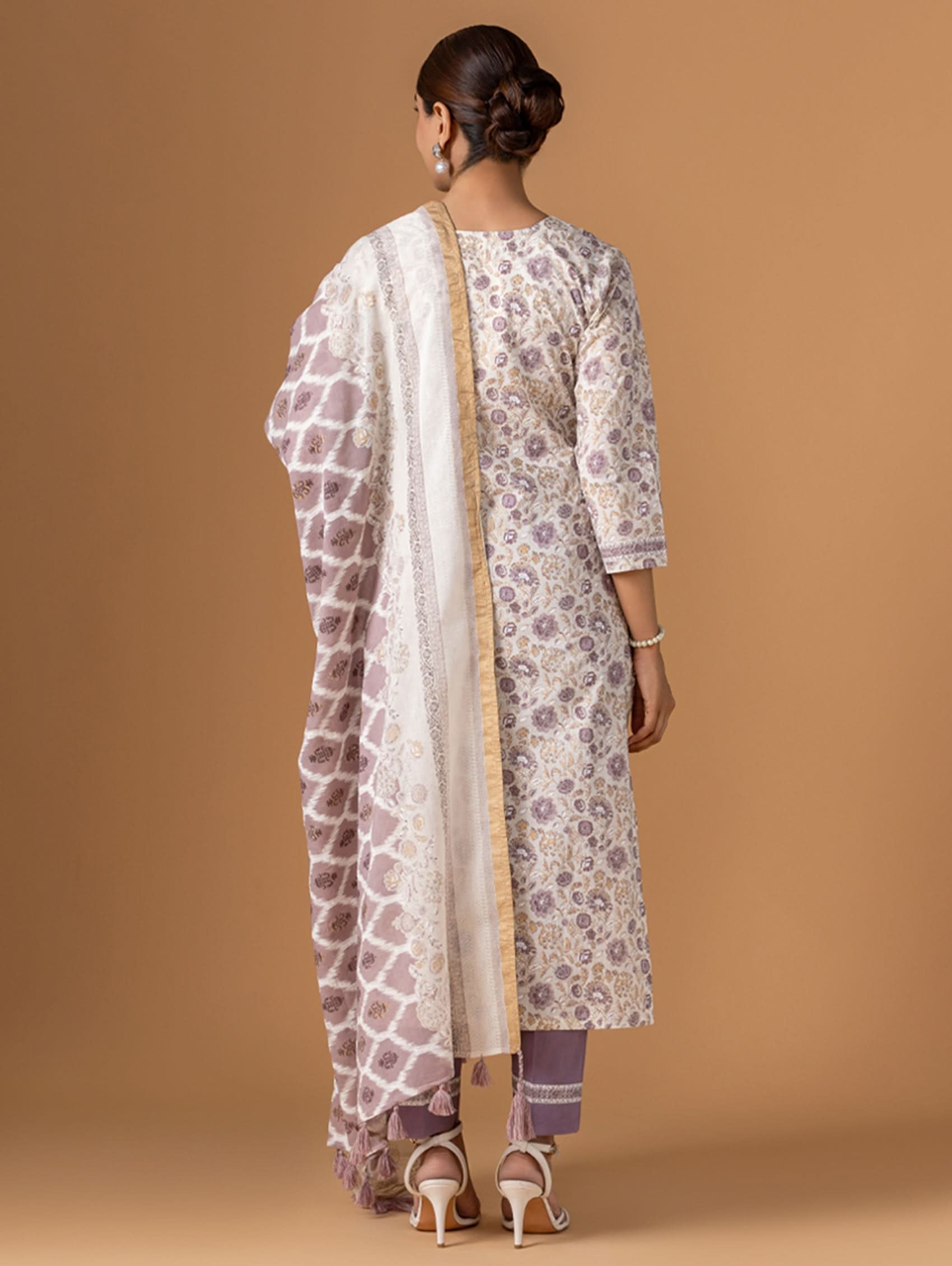 Woman wearing a patterned kurta with a white dupatta against a brown background