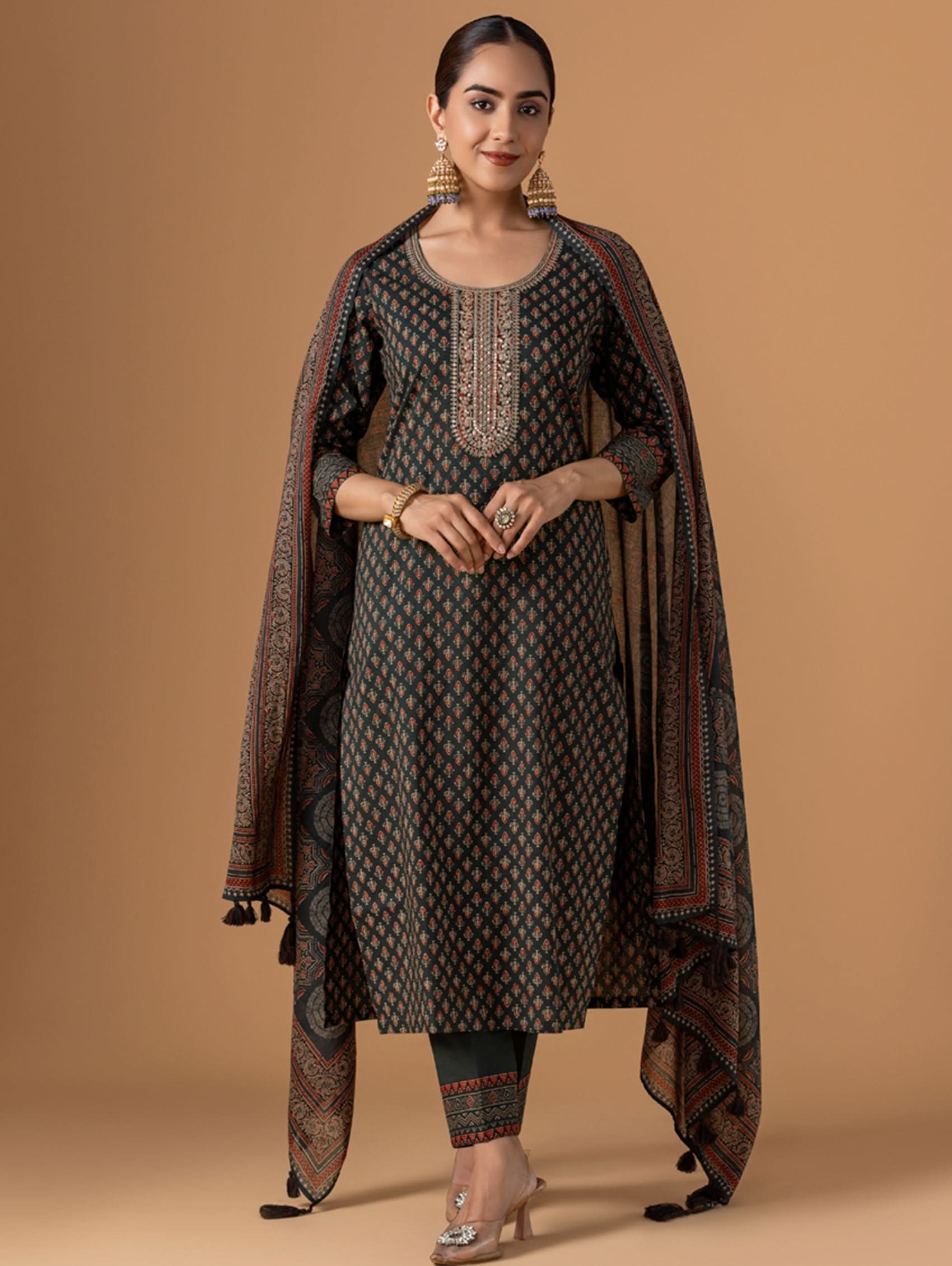 Woman wearing a traditional outfit with a patterned dress and dupatta on a beige background