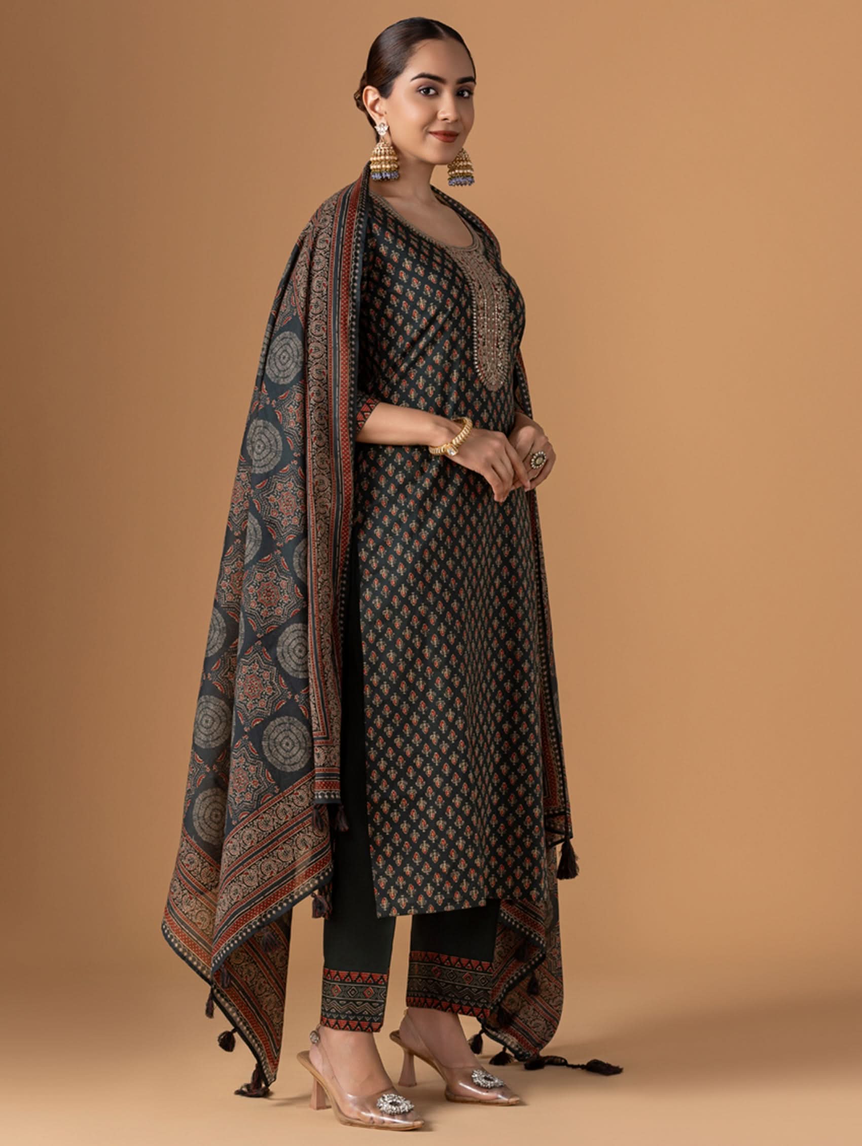 Woman wearing a traditional outfit with a patterned shawl against a beige background