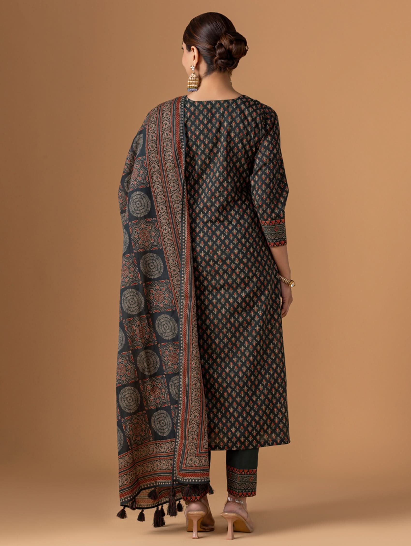 Woman wearing a traditional outfit with a patterned dupatta on a beige background
