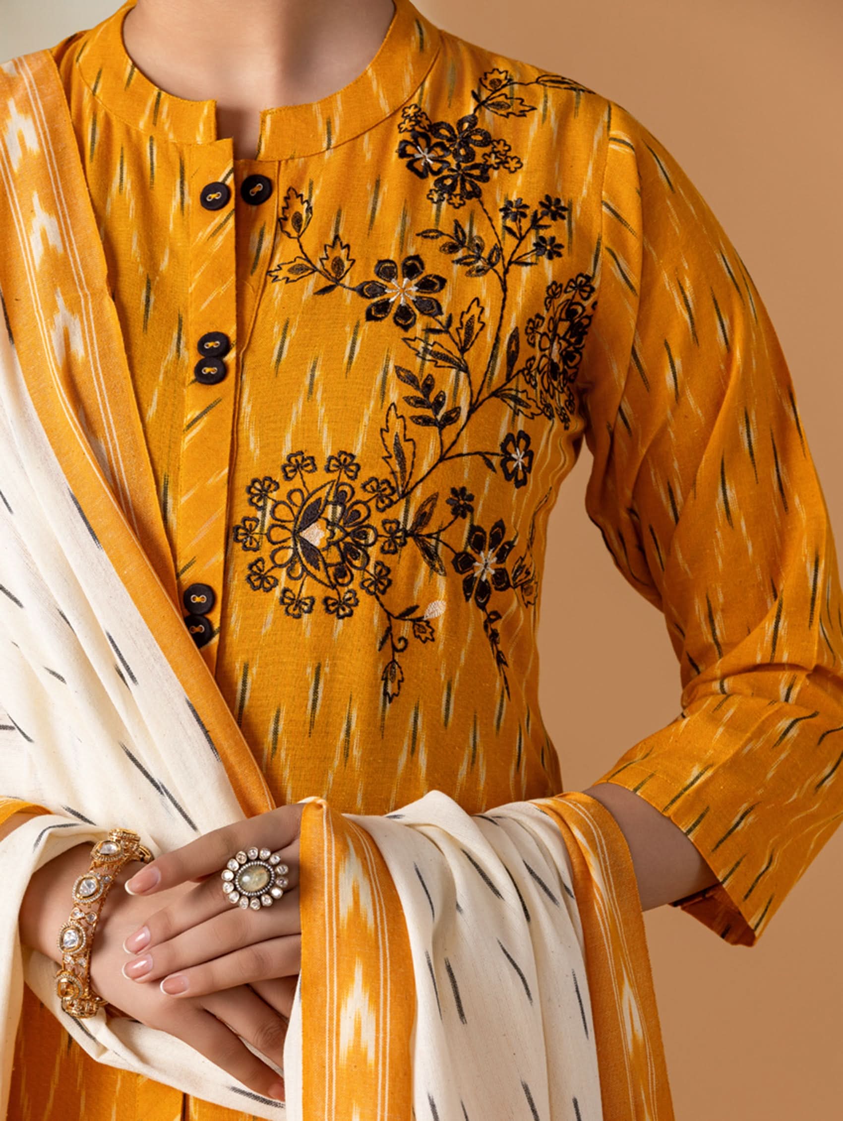 Yellow embroidered traditional outfit with a beige background