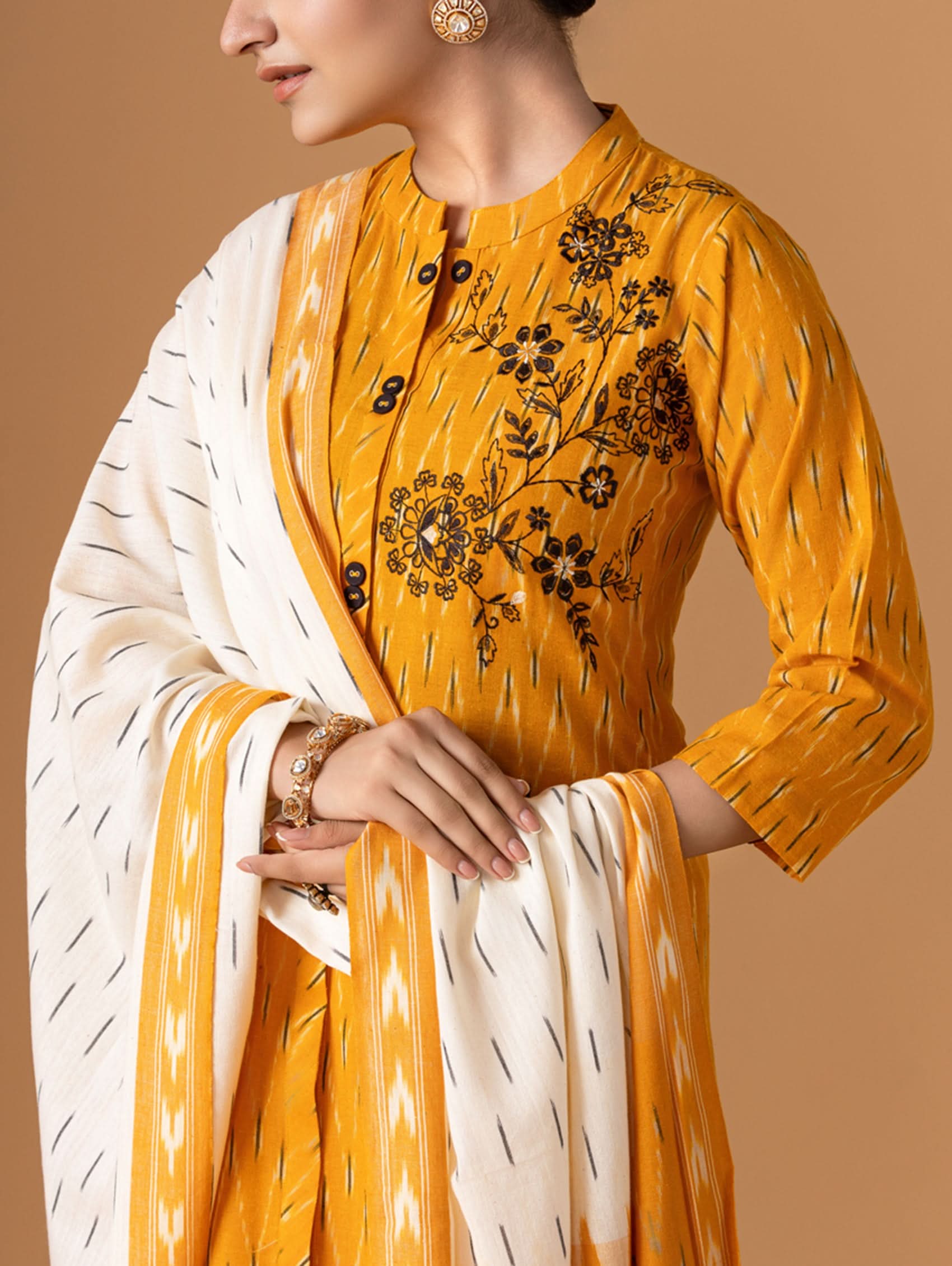 Yellow embroidered kurta with white dupatta on a brown background
