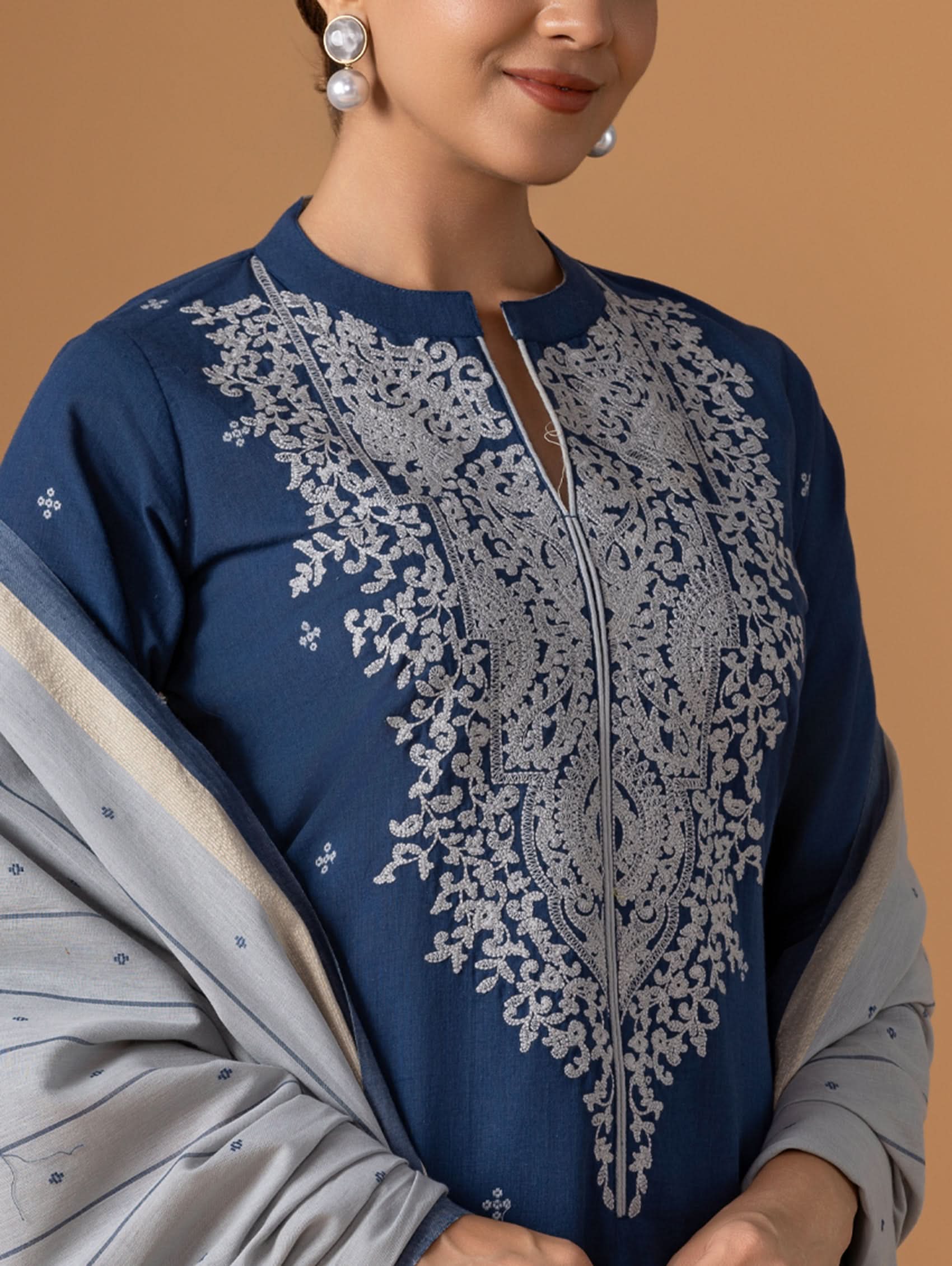 Navy blue top with intricate silver embroidery on a beige background