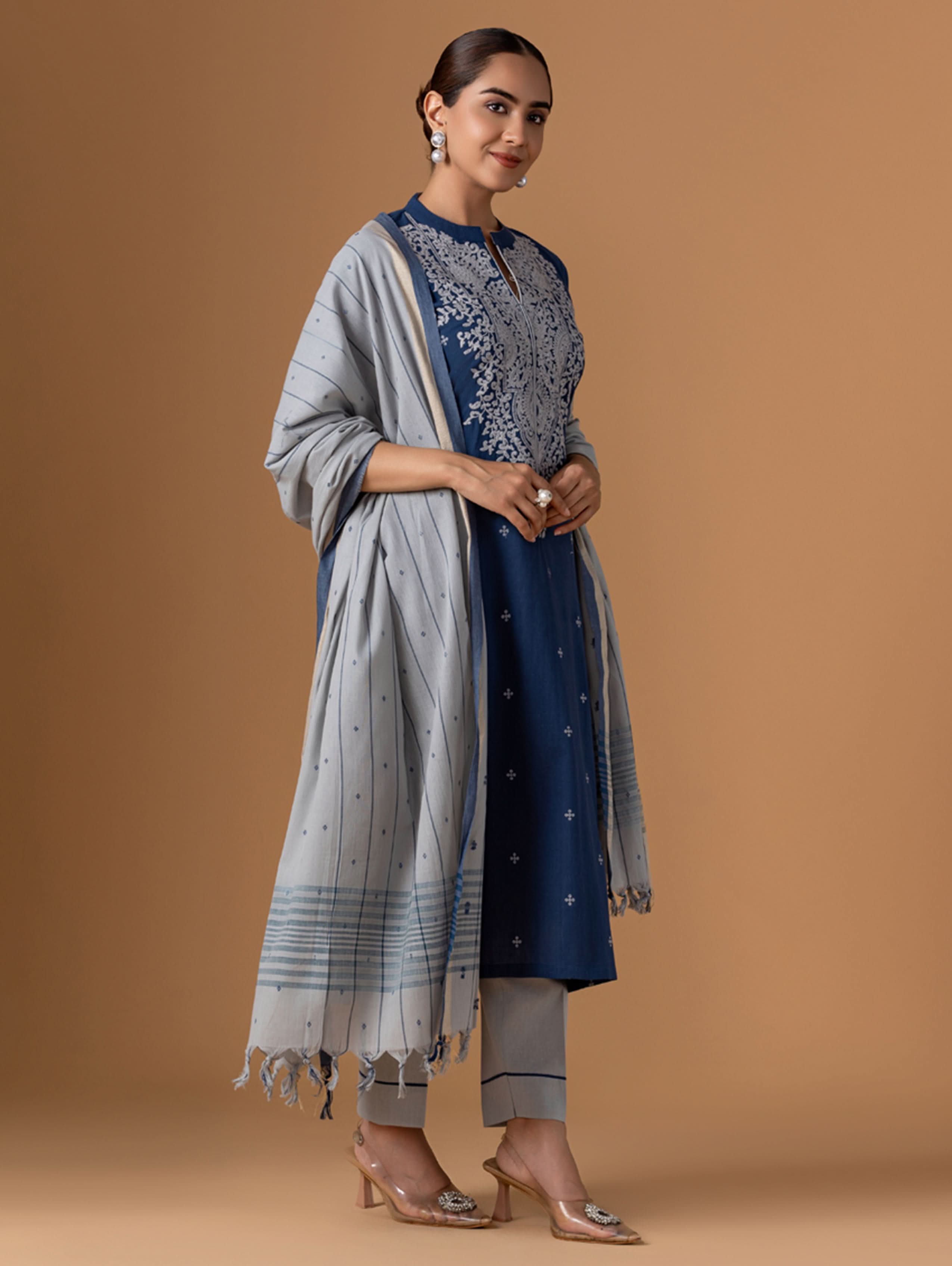 Woman wearing a blue and gray traditional outfit with a beige background
