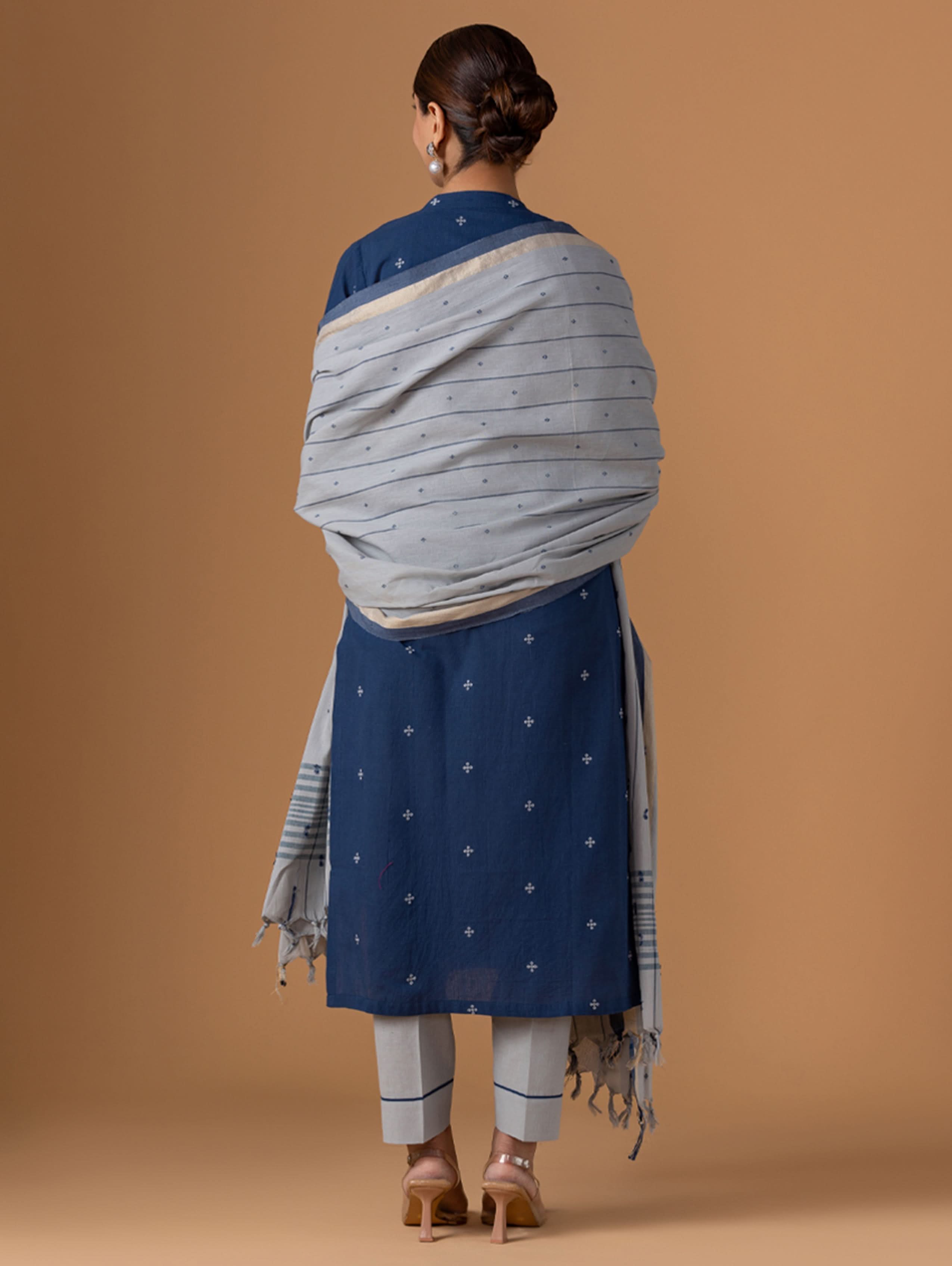Woman wearing a blue and gray traditional outfit on a brown background