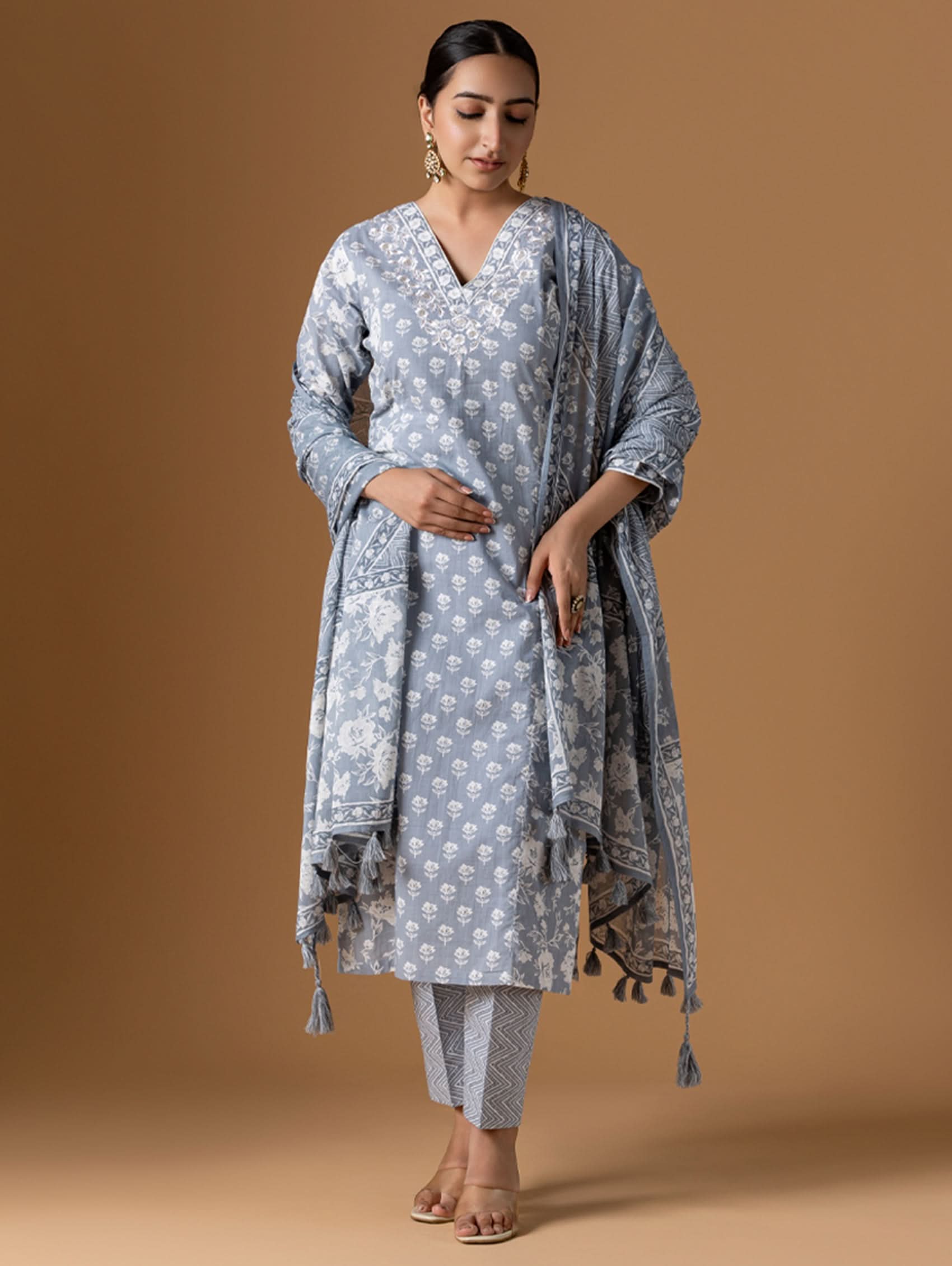 Woman wearing a light blue traditional outfit with a matching dupatta on a brown background