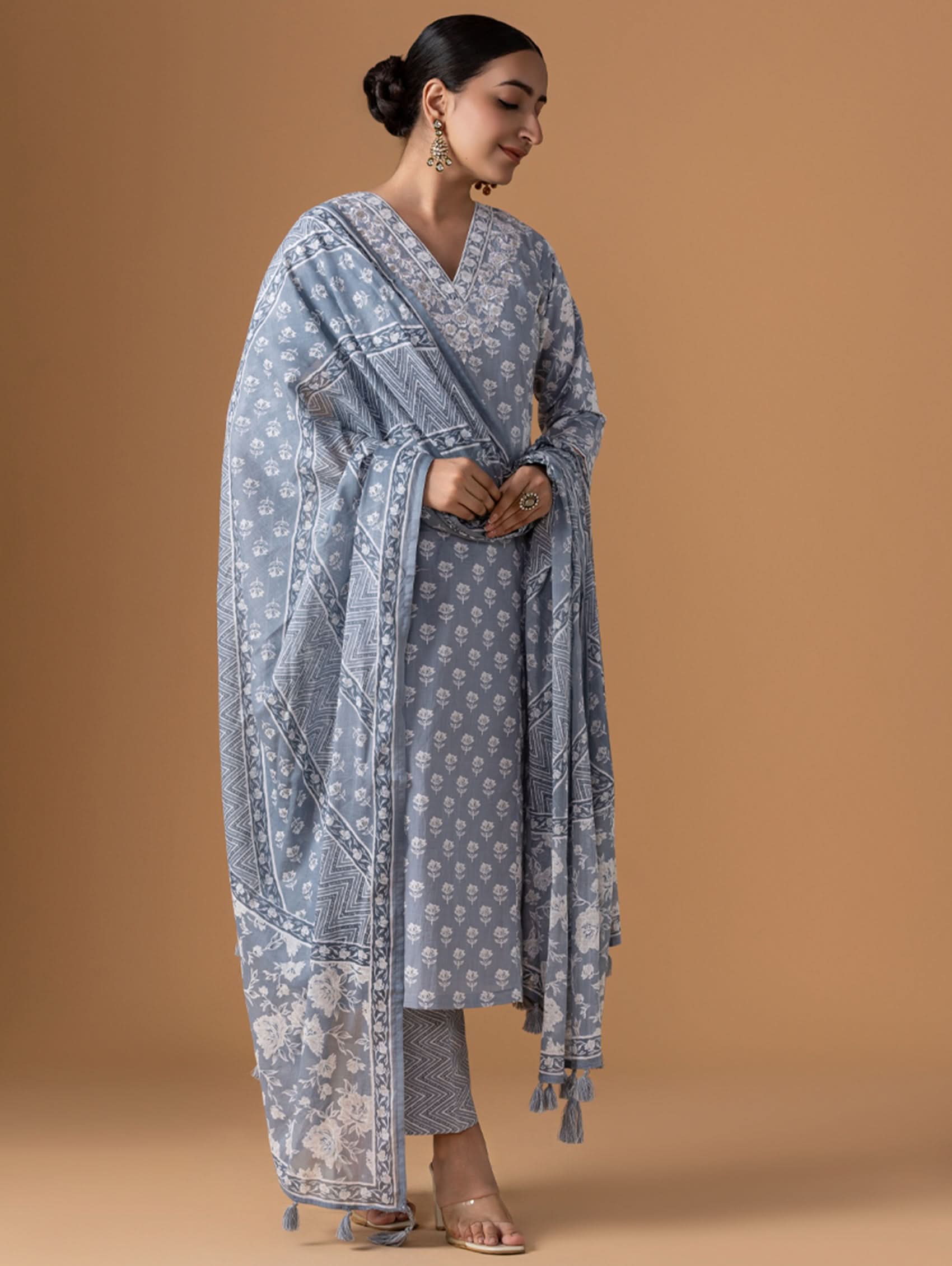 Woman wearing a light blue traditional outfit with a matching dupatta on a brown background