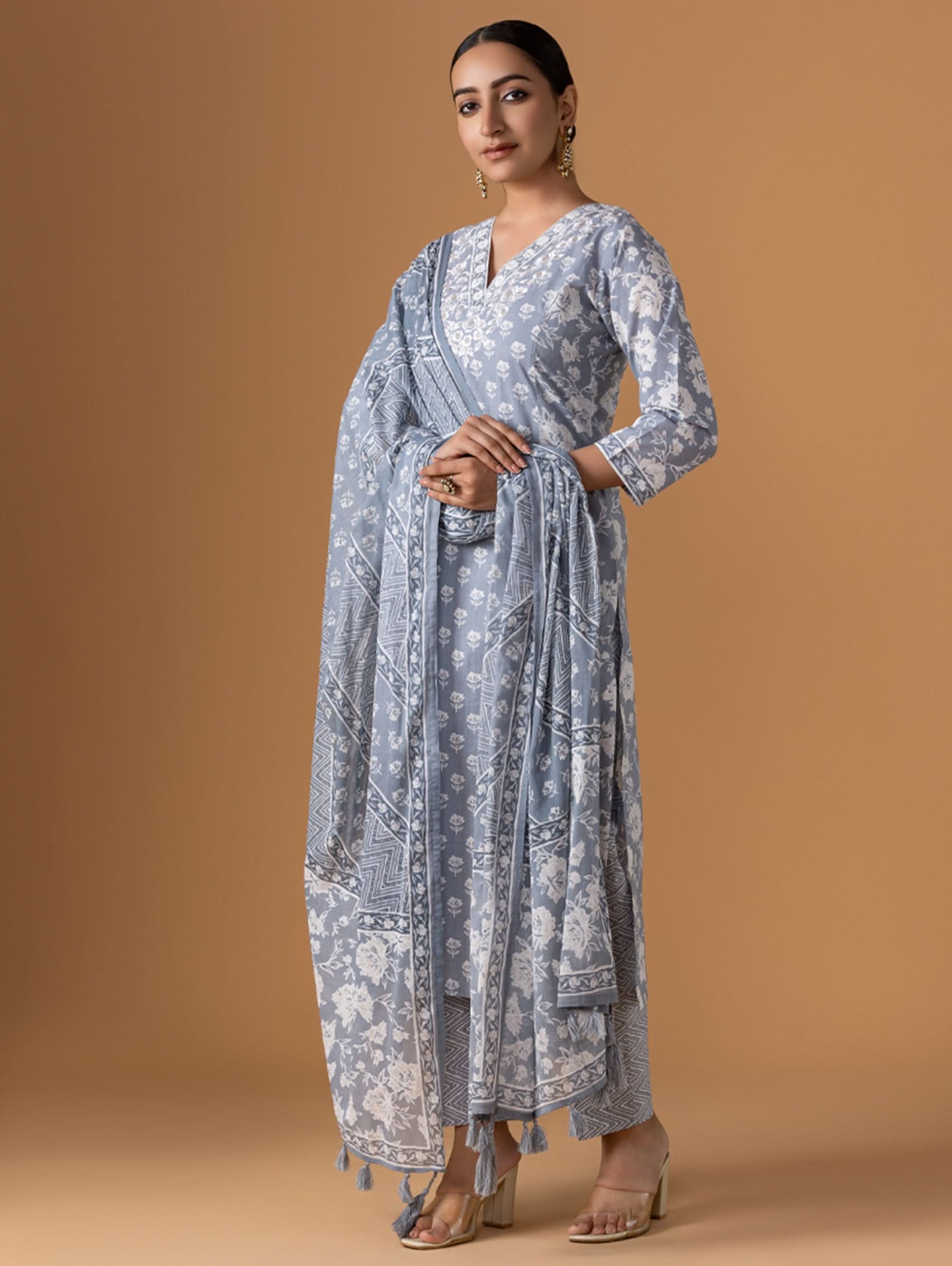 Woman wearing a long, light blue patterned dress against a brown background