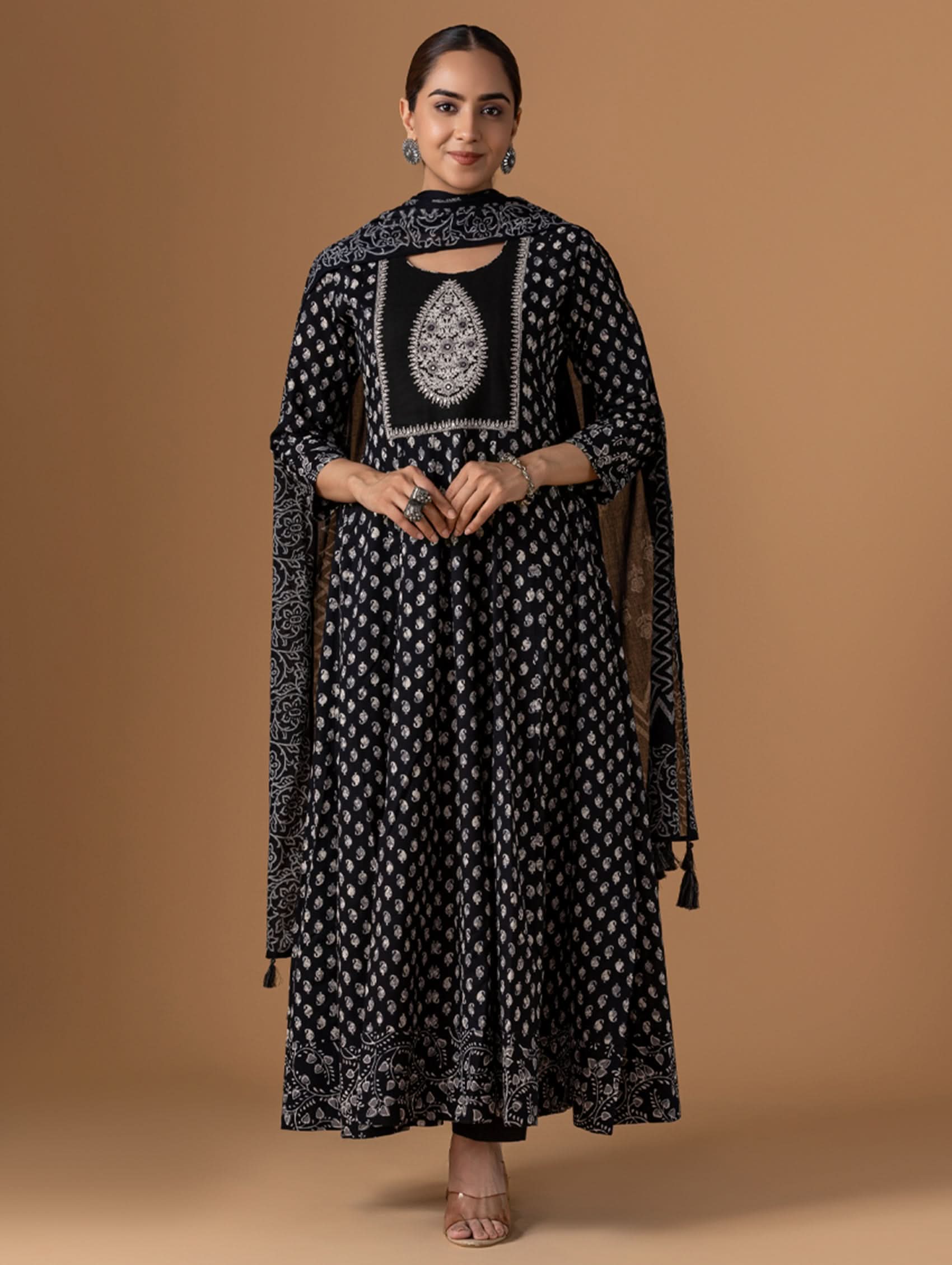 Woman wearing a black and white patterned outfit with a matching shawl on a brown background