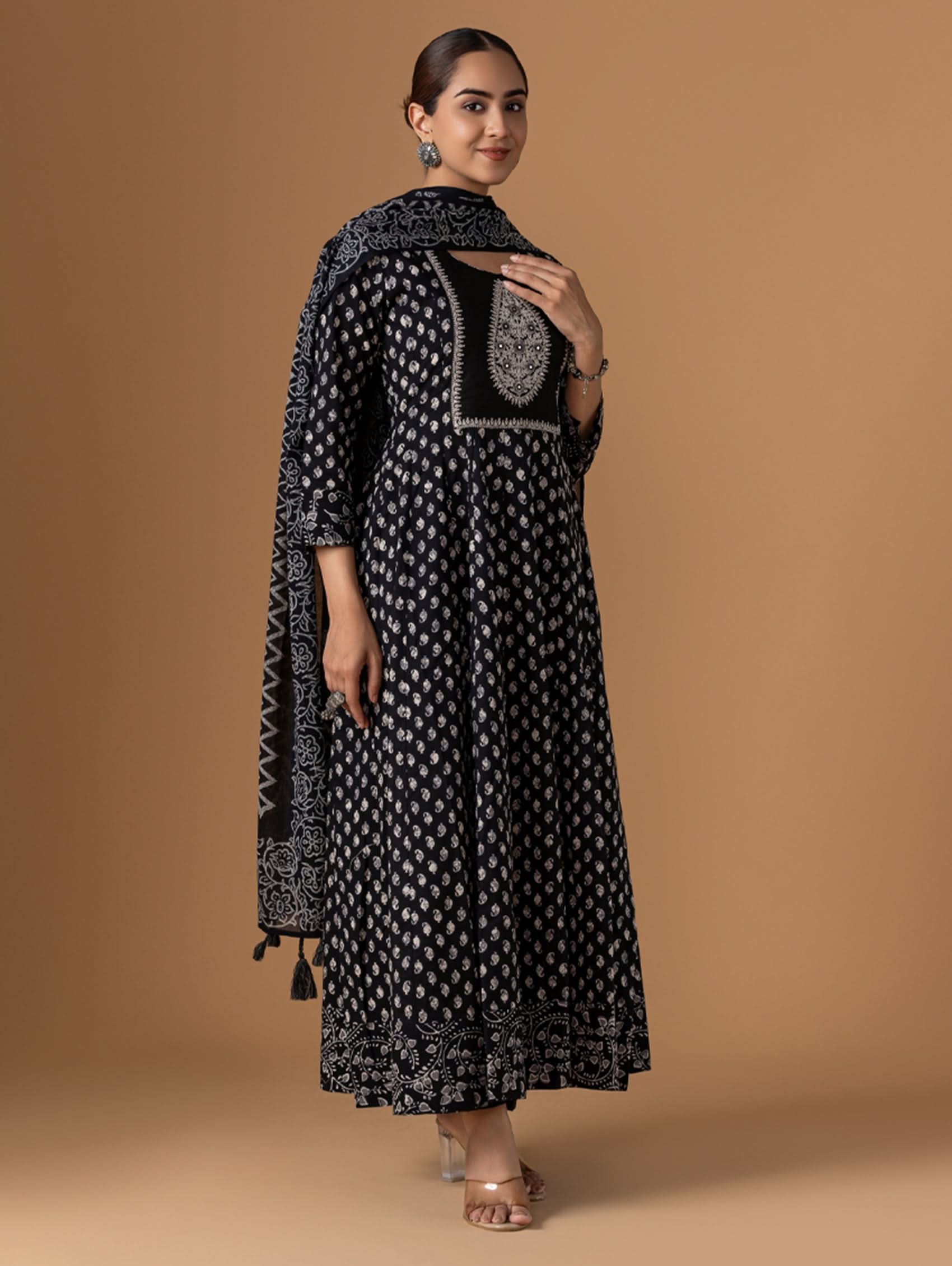 Woman wearing a black and white patterned outfit with a matching shawl on a brown background