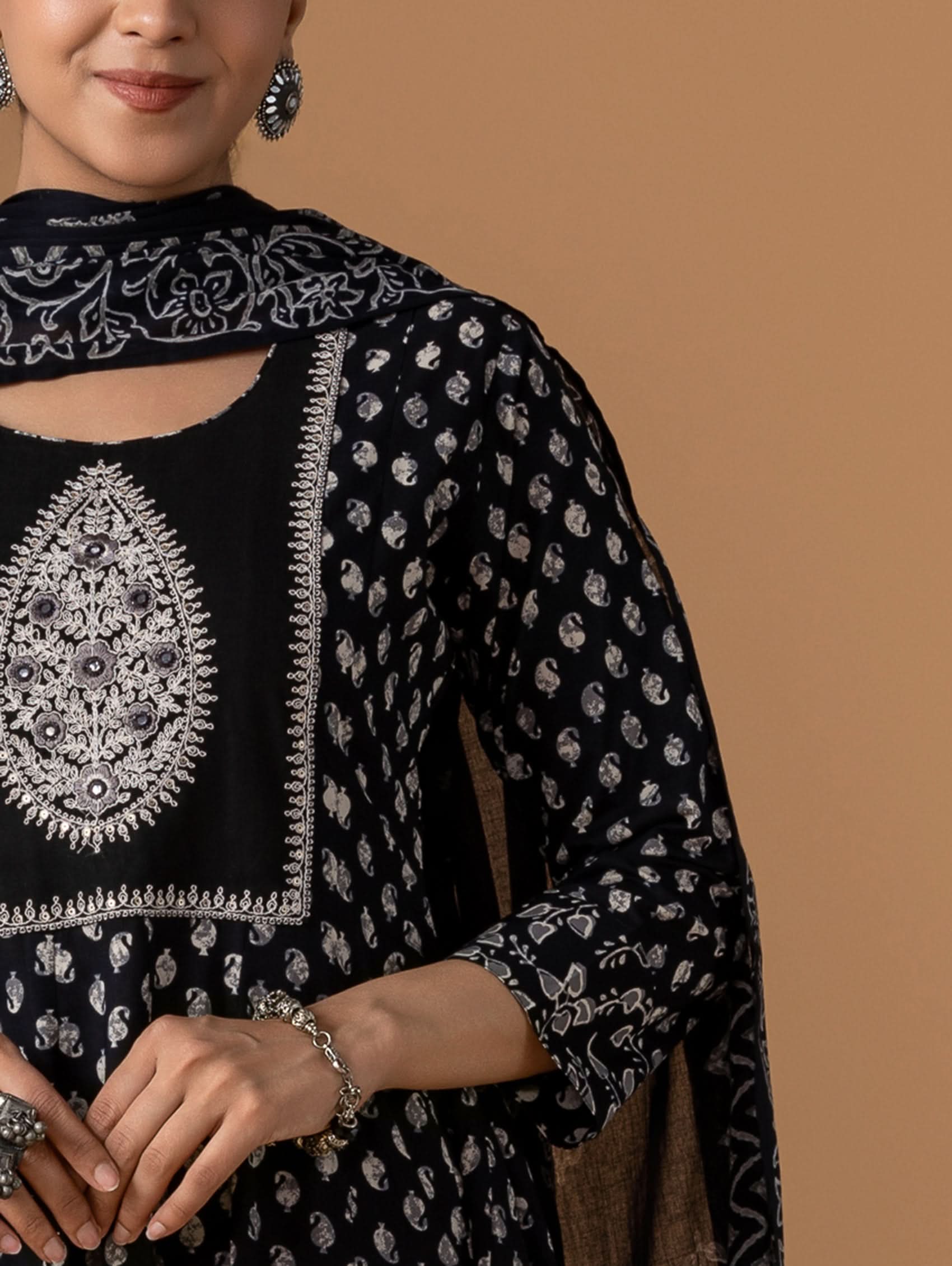Black traditional outfit with silver embroidery on a brown background