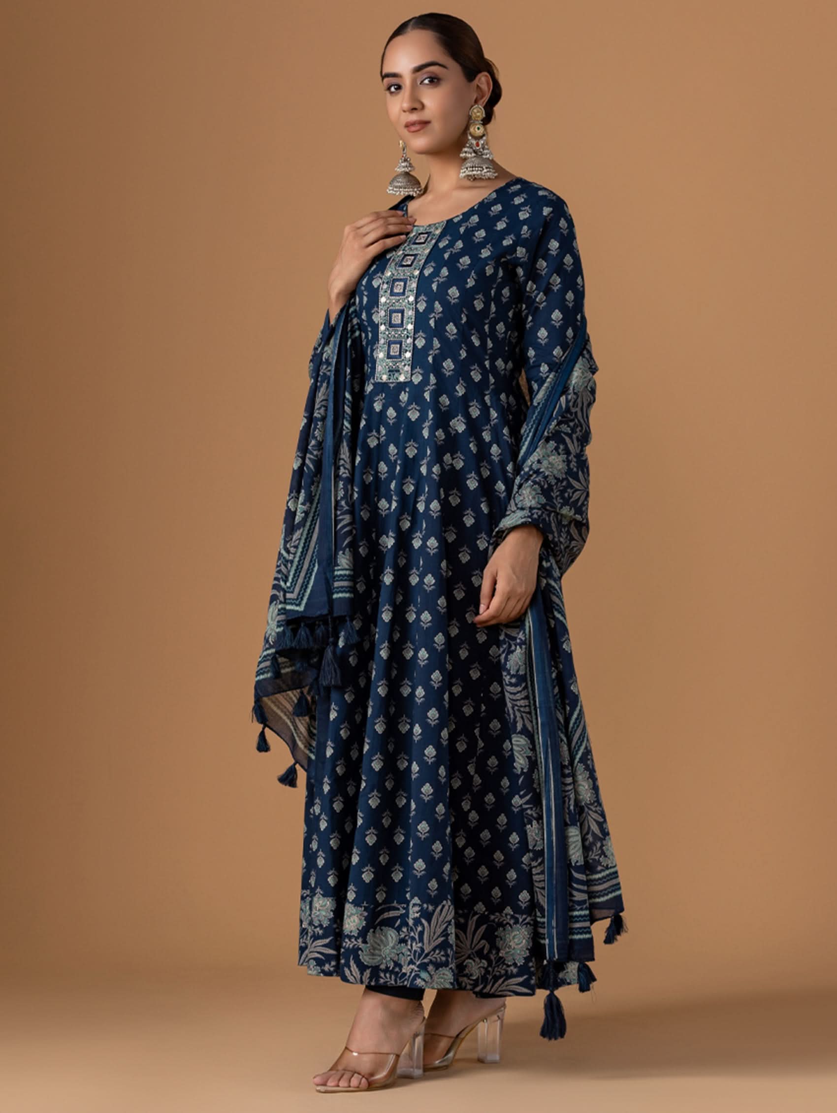 Woman wearing a blue patterned outfit with a matching dupatta on a brown background