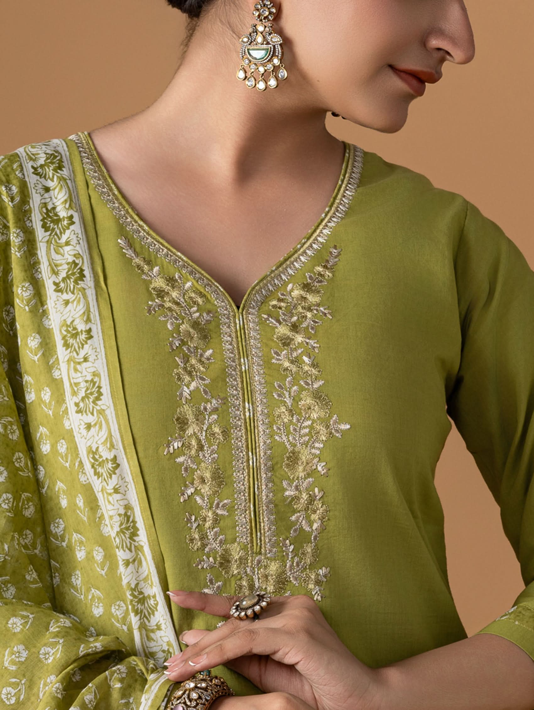 Green embroidered traditional outfit with a neutral background
