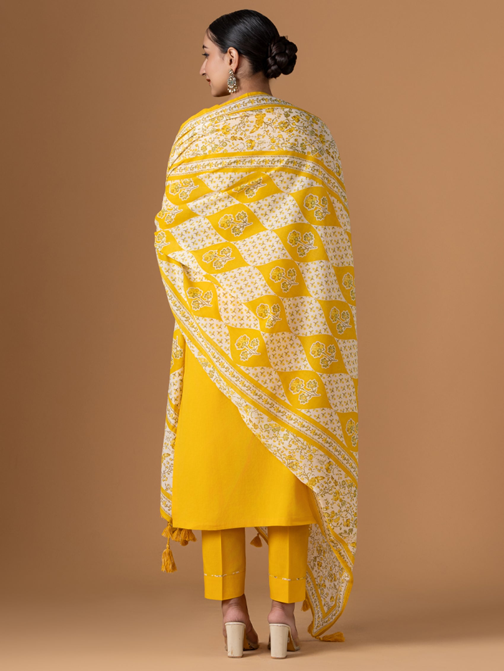 Woman wearing a yellow and white patterned dupatta on a beige background