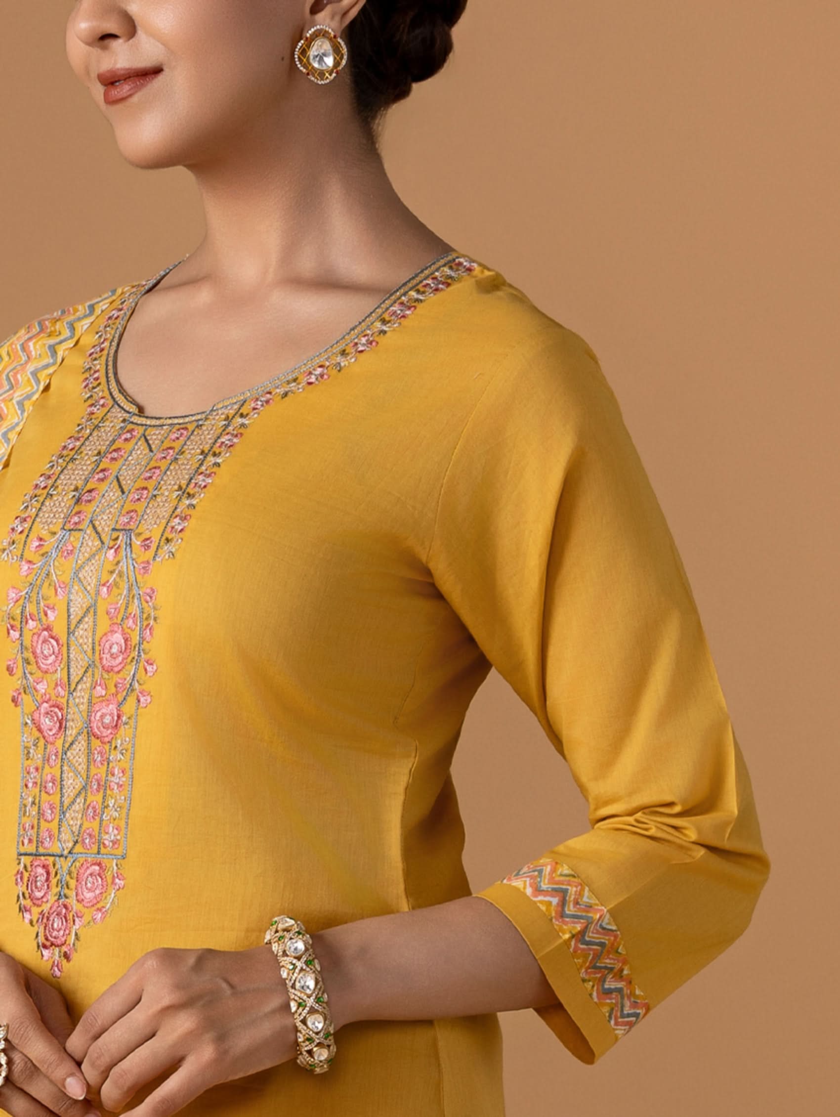 Yellow kurta with intricate embroidery on a brown background