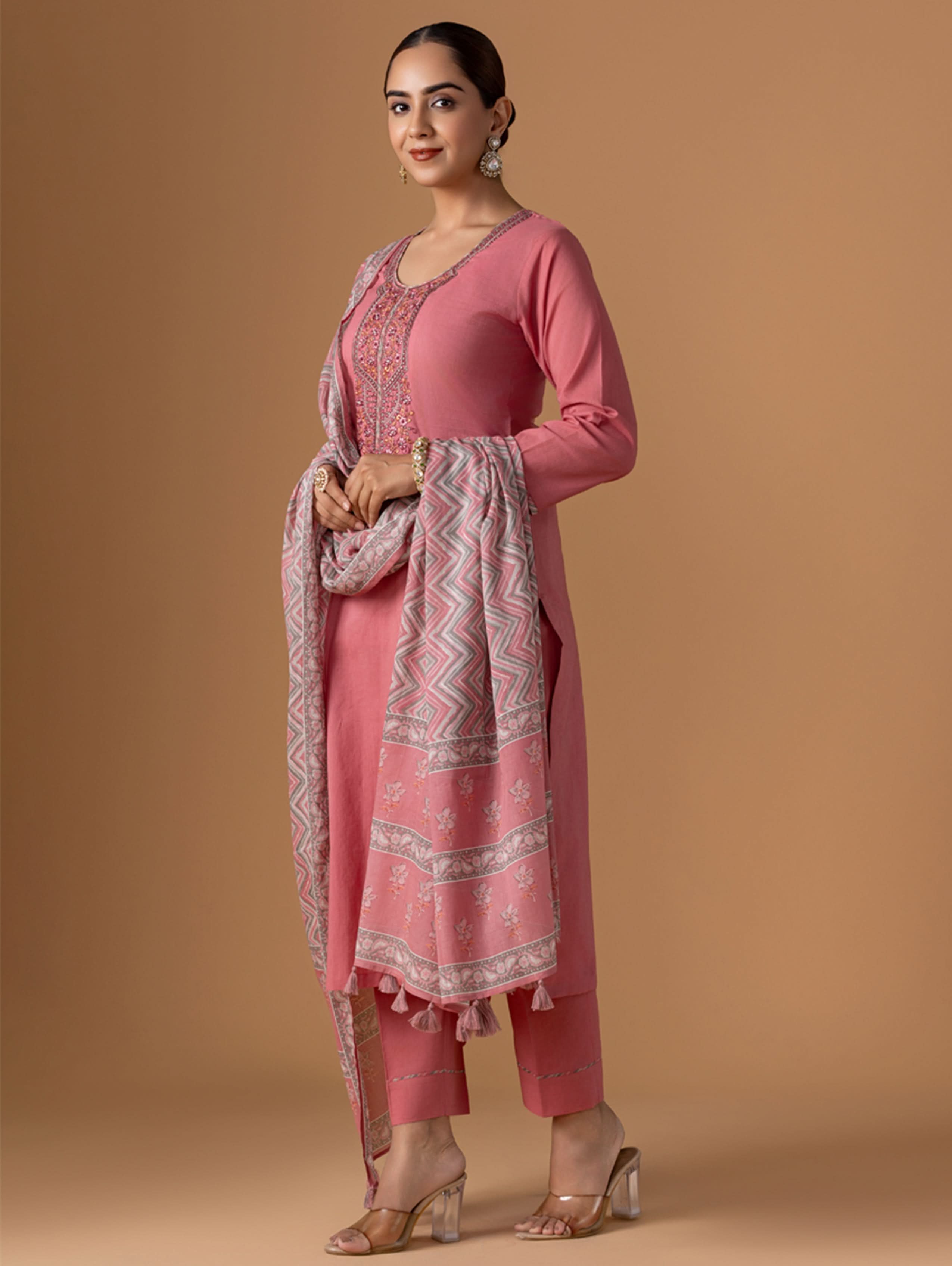 Woman wearing a pink traditional outfit with a patterned dupatta against a beige background