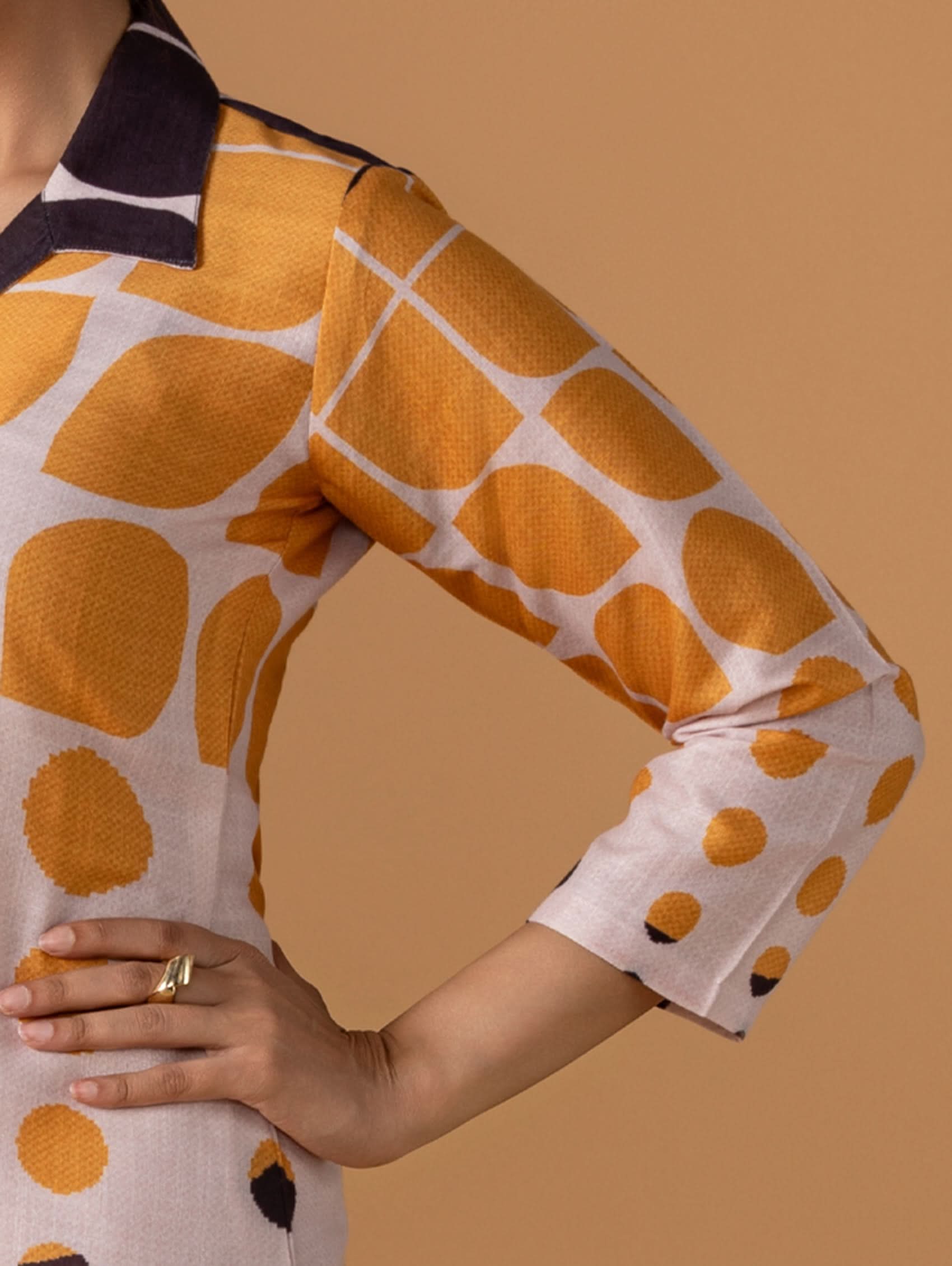 Close-up of a person wearing a patterned shirt with orange and white design on a beige background