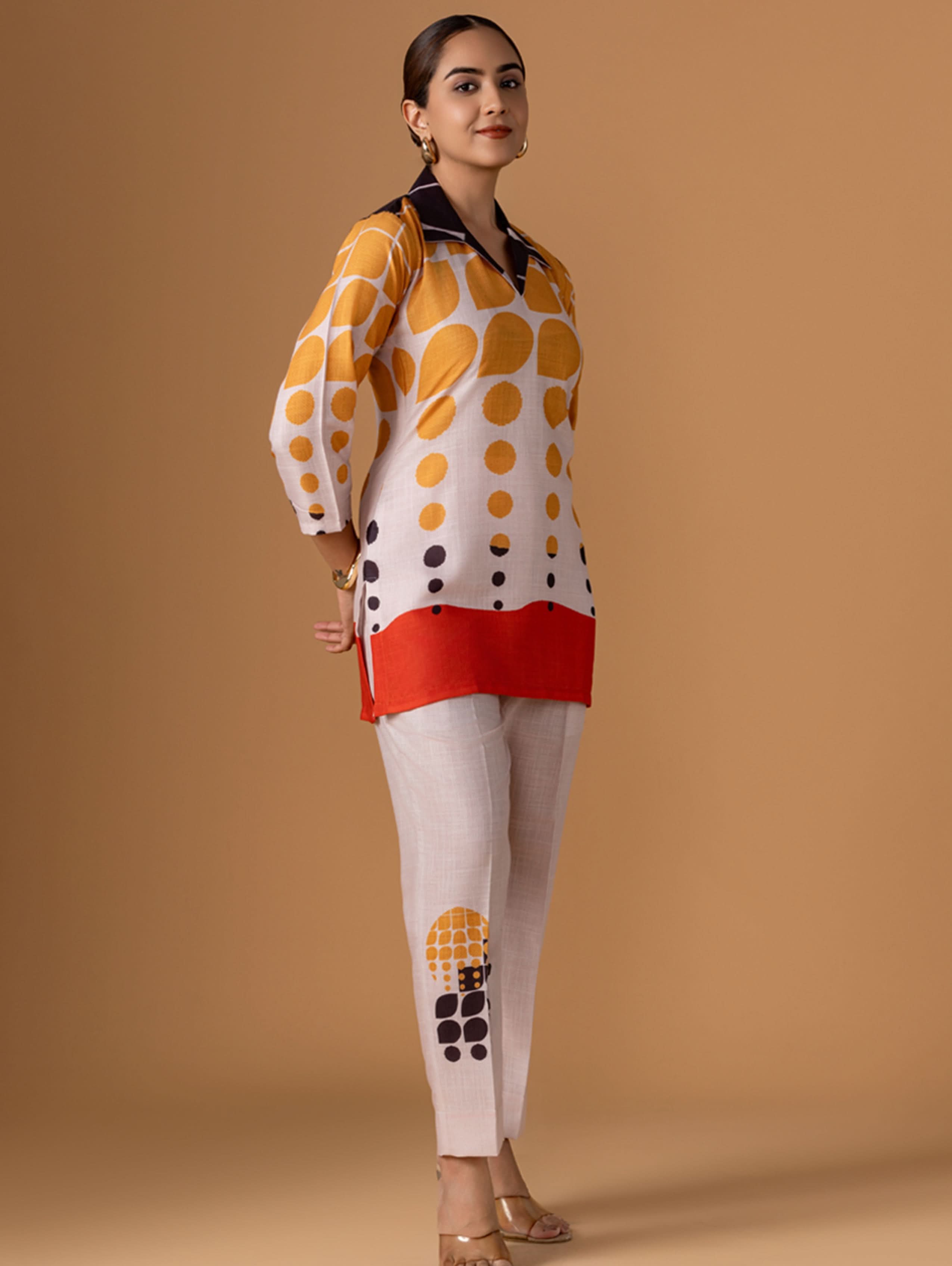 Woman wearing a polka dot blouse and pants against a beige background