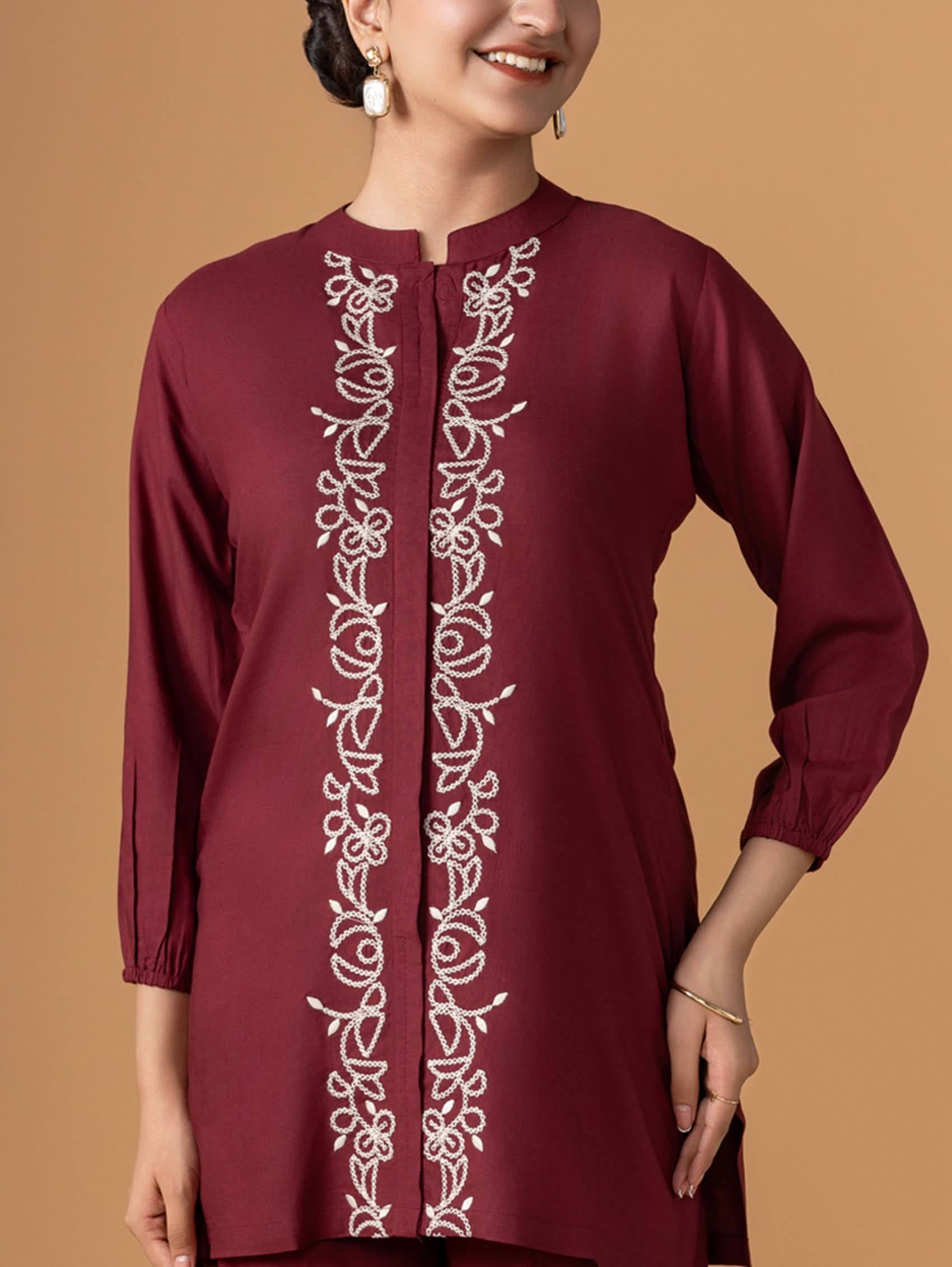 Maroon kurta with white embroidery on a brown background