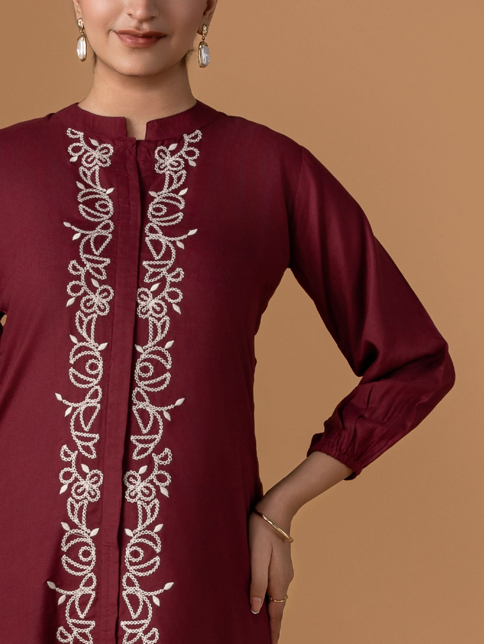 Maroon dress with white embroidery on a brown background