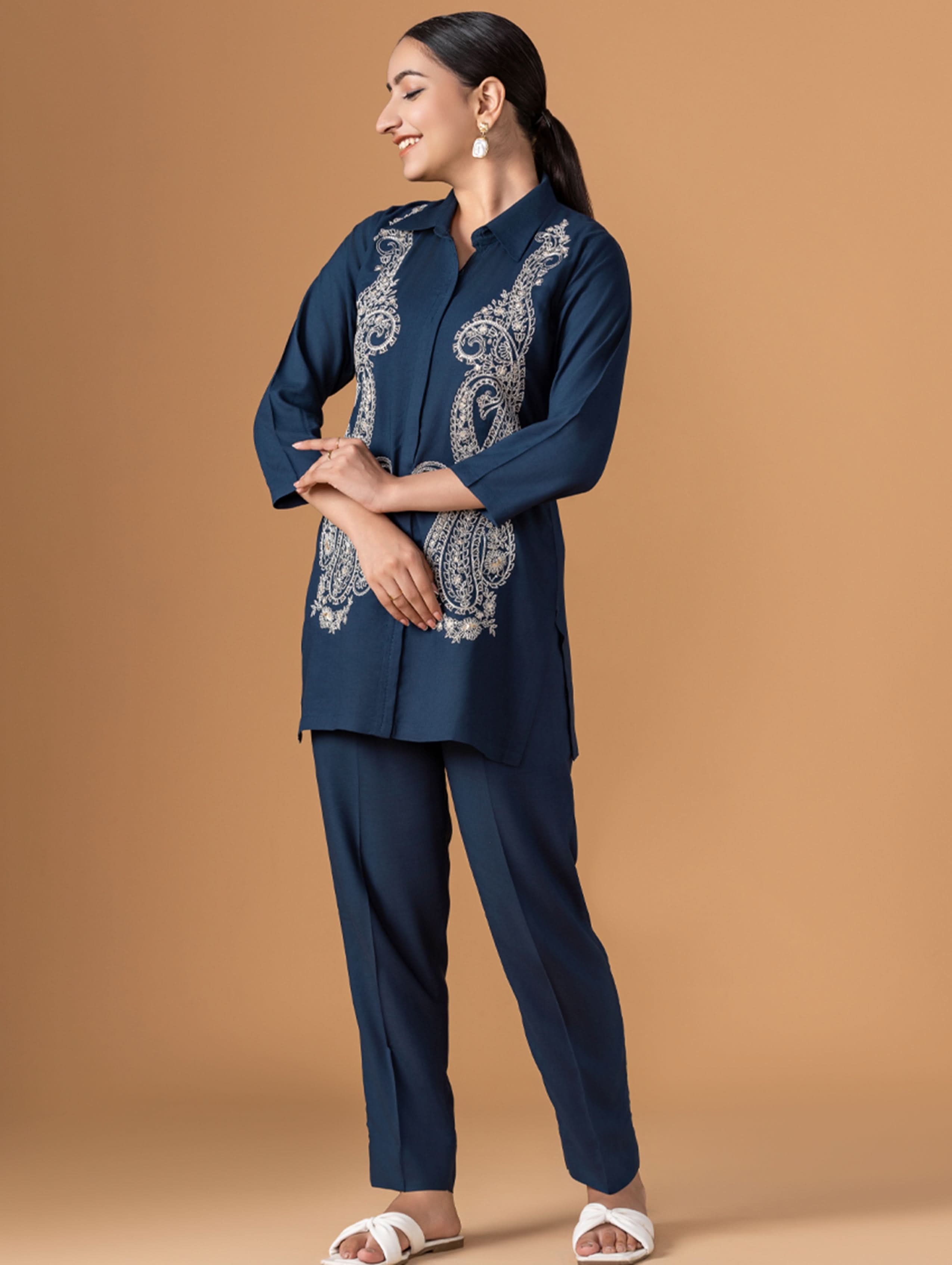 Woman wearing a navy blue outfit with intricate white patterns on a beige background
