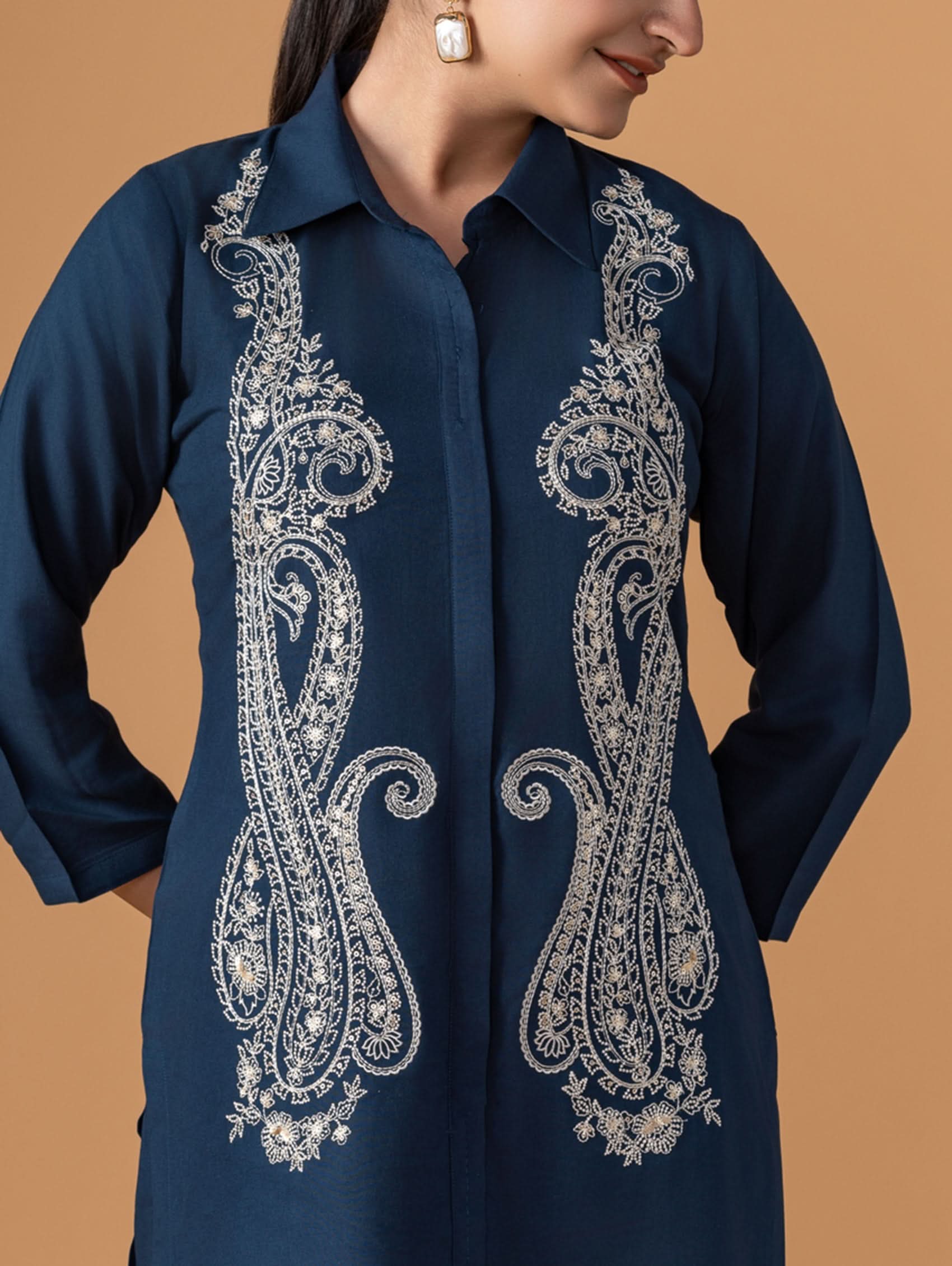 Navy blue shirt with intricate white embroidery on a beige background