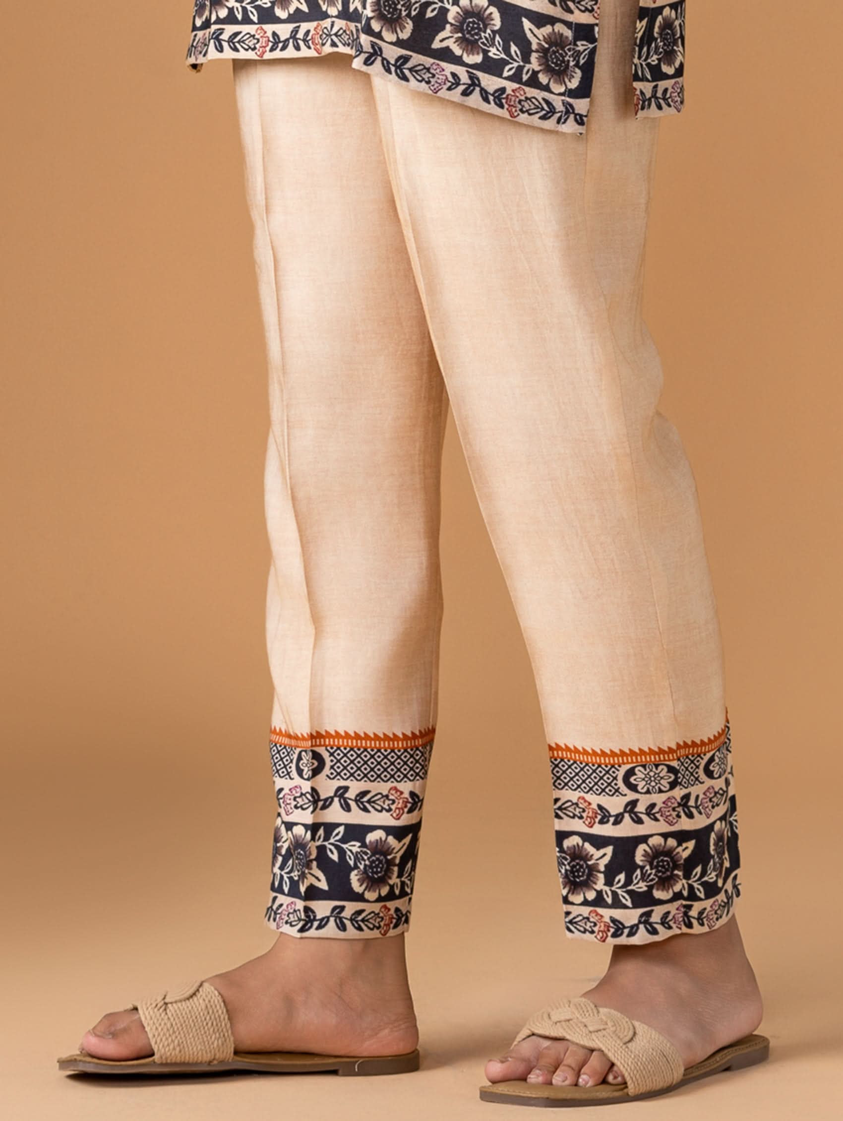Beige pants with floral patterns at the bottom on a beige background