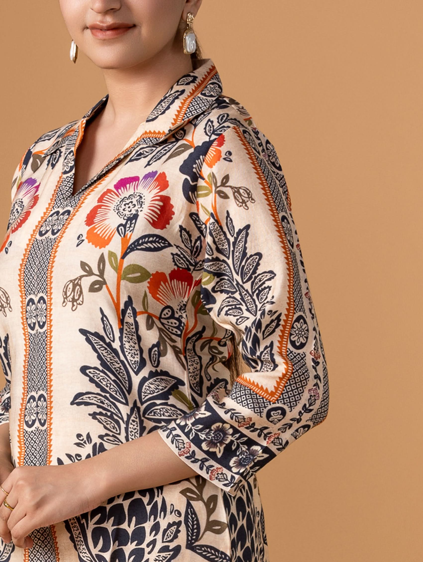 Woman wearing a patterned outfit with floral and abstract designs on a beige background
