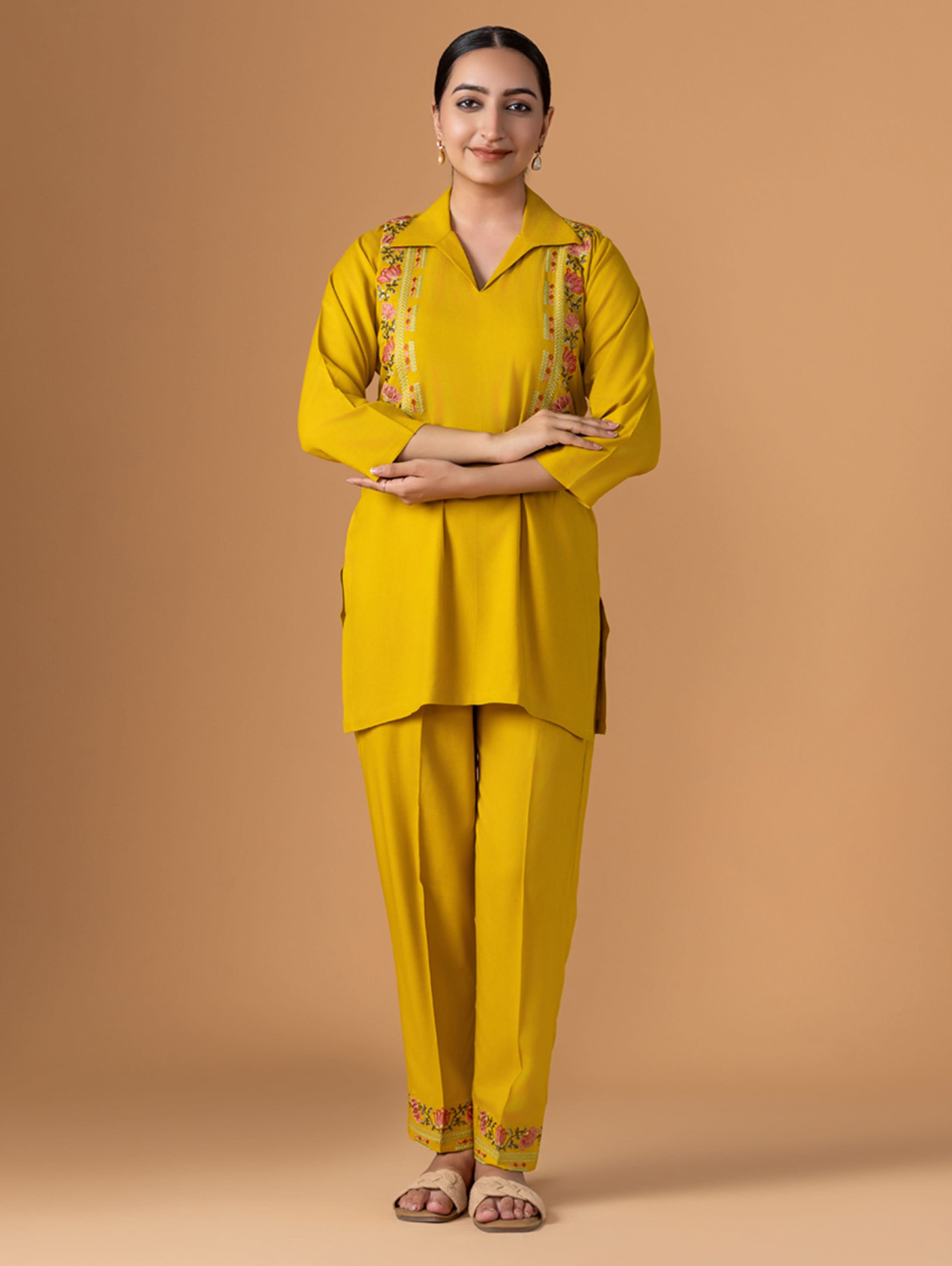 Woman wearing a yellow traditional outfit with floral patterns on a beige background