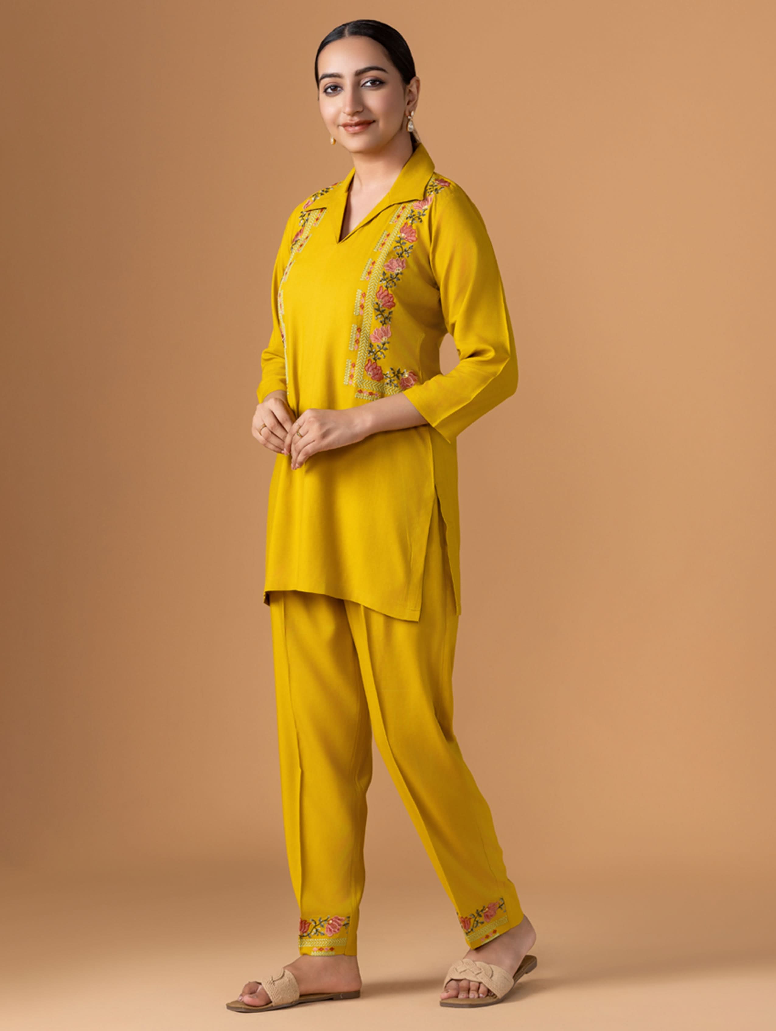 Woman wearing a yellow traditional outfit with floral patterns on a beige background