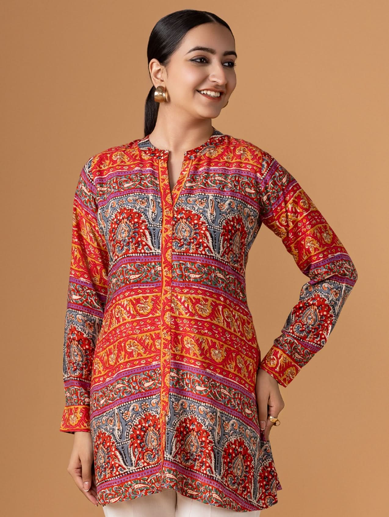 Woman wearing a colorful patterned shirt against a brown background