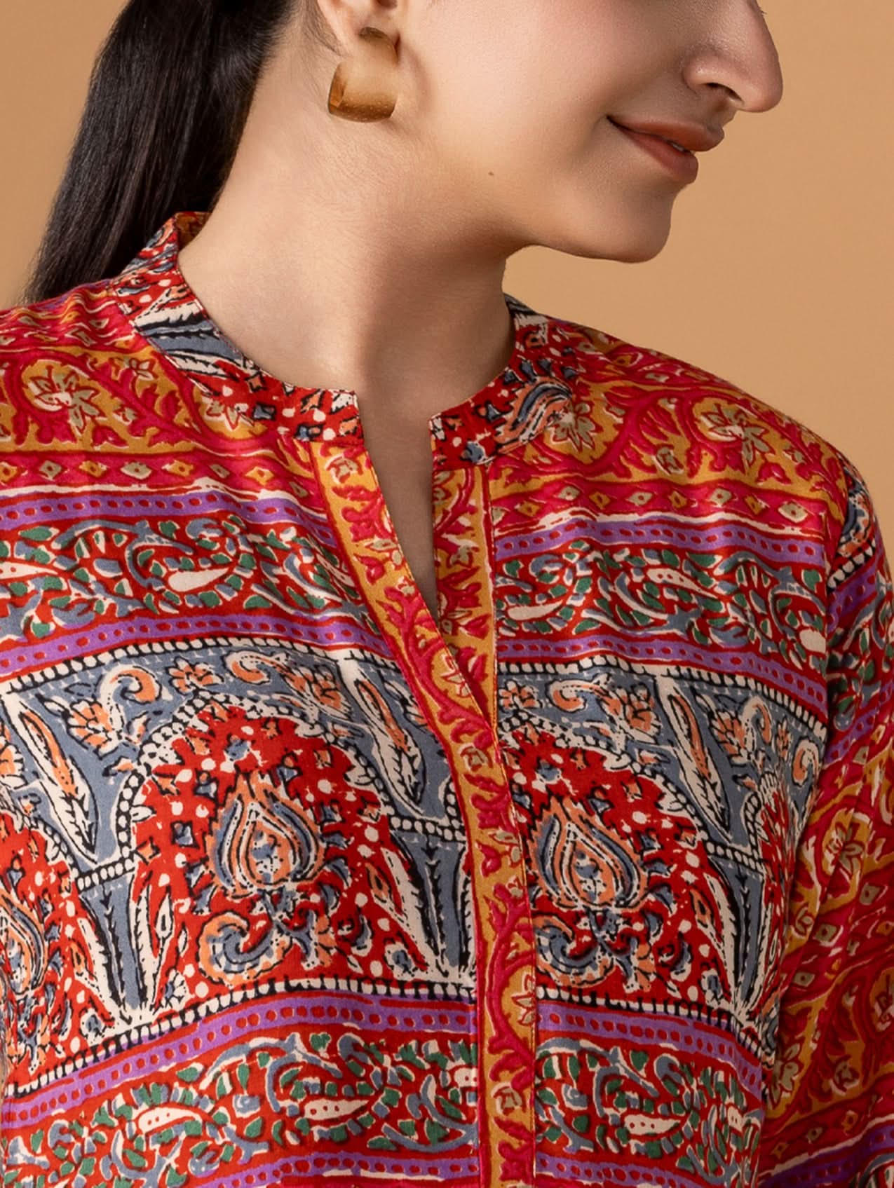 Close-up of a person wearing a colorful patterned shirt against a beige background