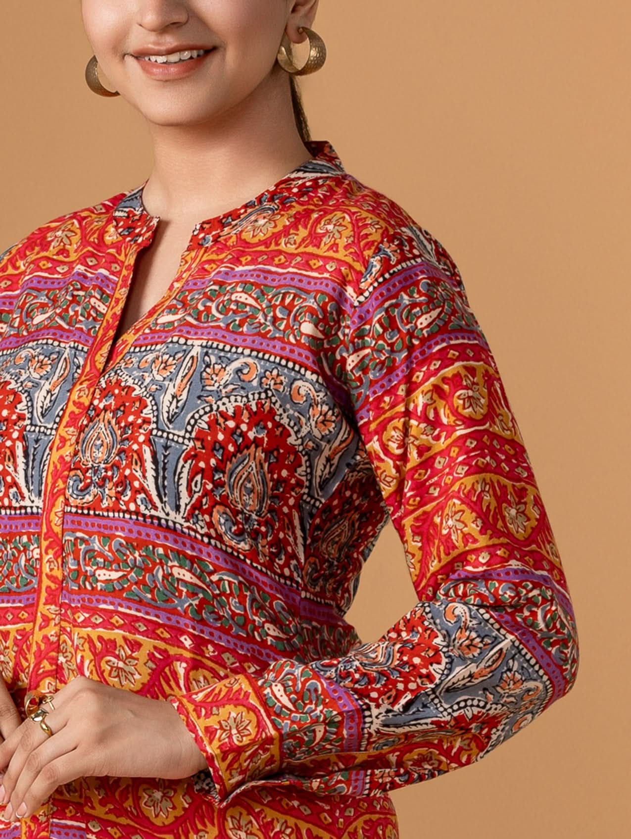 Woman wearing a colorful patterned shirt against a beige background