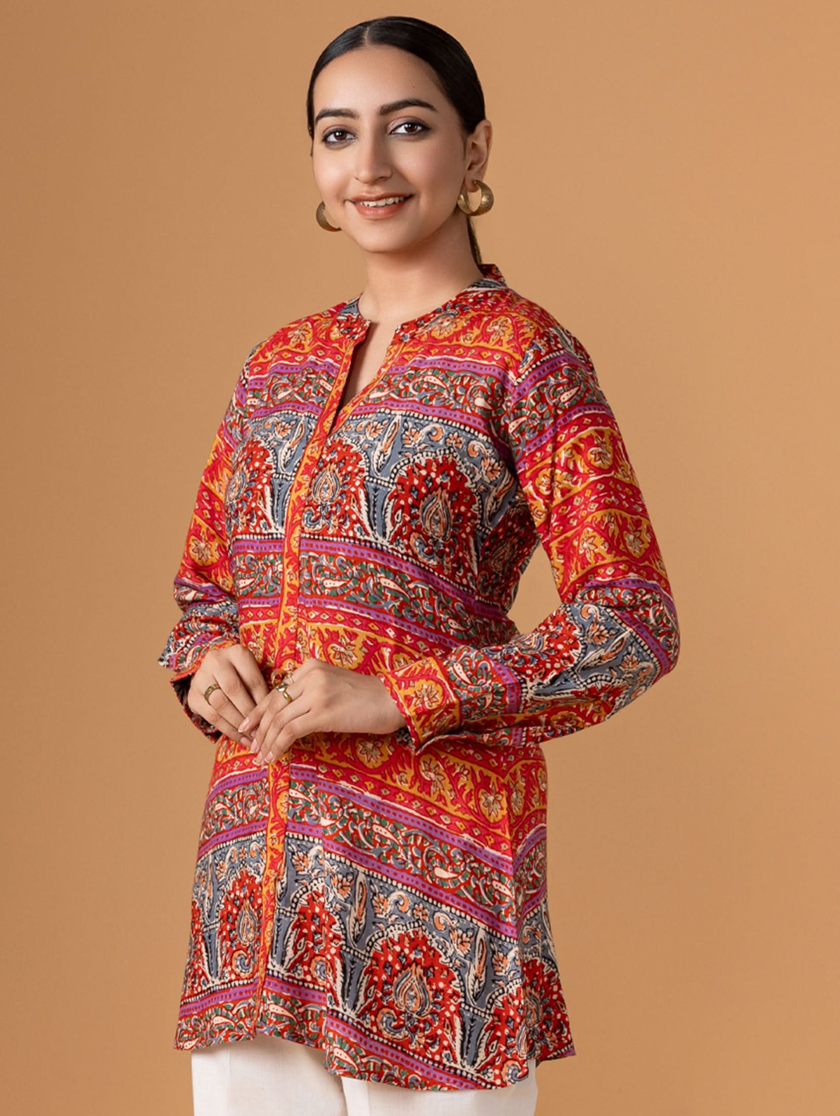 Woman wearing a colorful patterned kurta against a beige background
