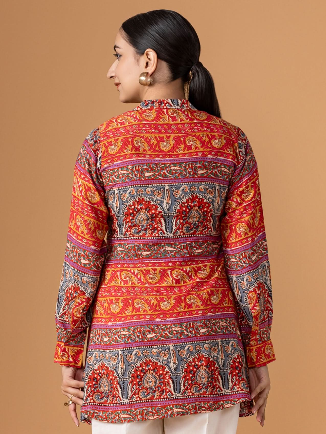 Woman wearing a colorful patterned shirt against a brown background
