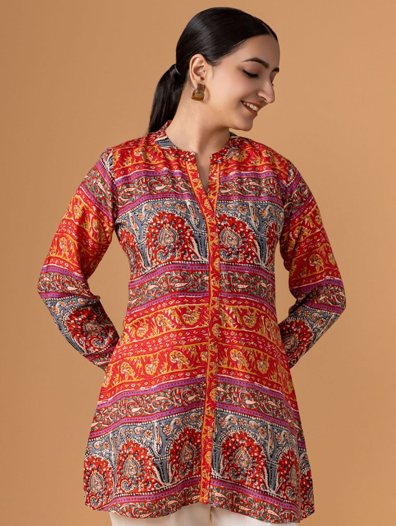 Woman wearing a colorful patterned shirt against a beige background