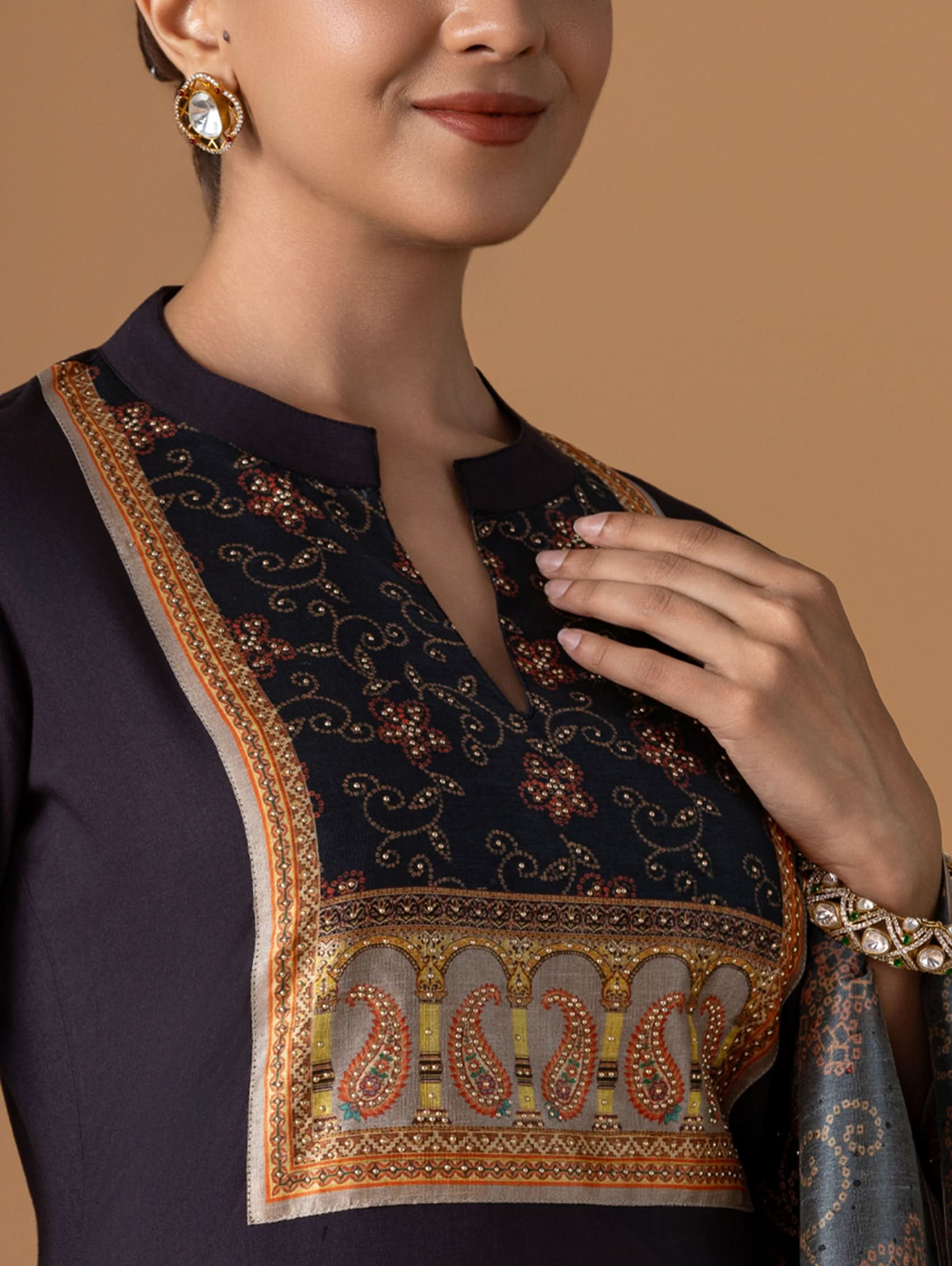 Woman wearing a dark blue outfit with intricate paisley patterns on a beige background