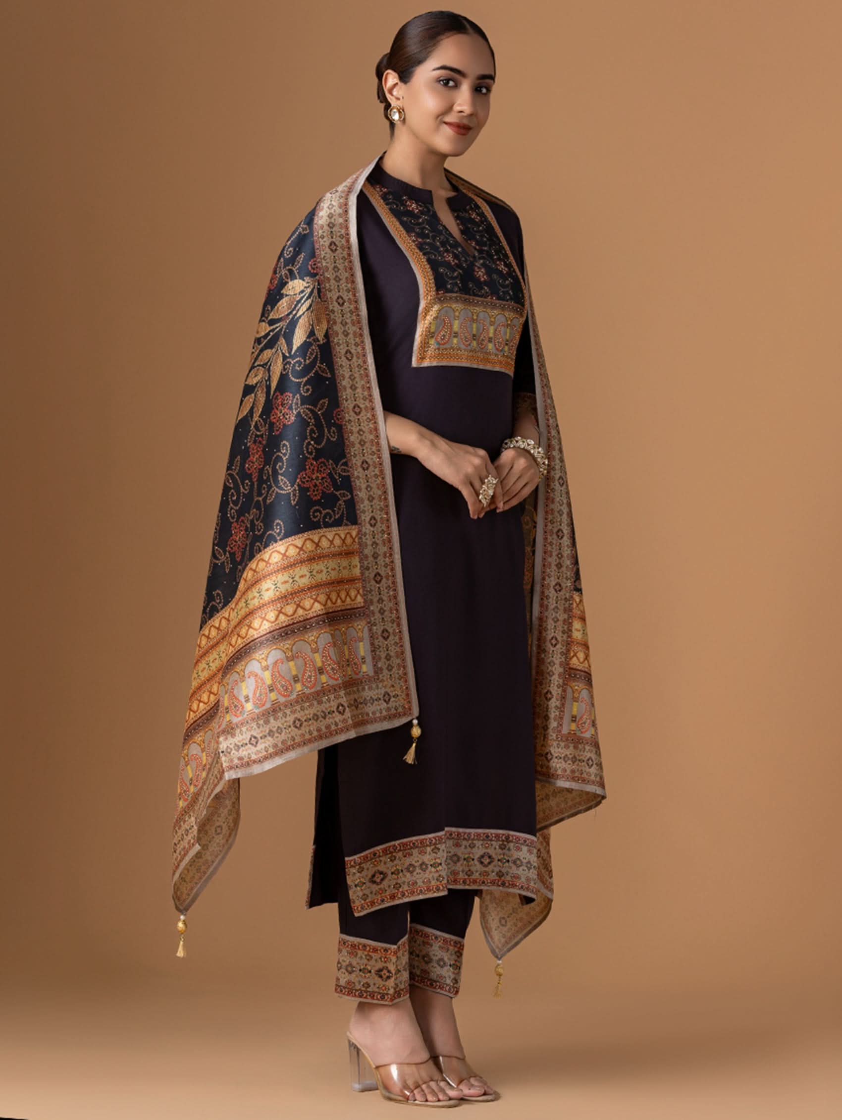 Woman wearing a traditional outfit with a patterned shawl on a brown background