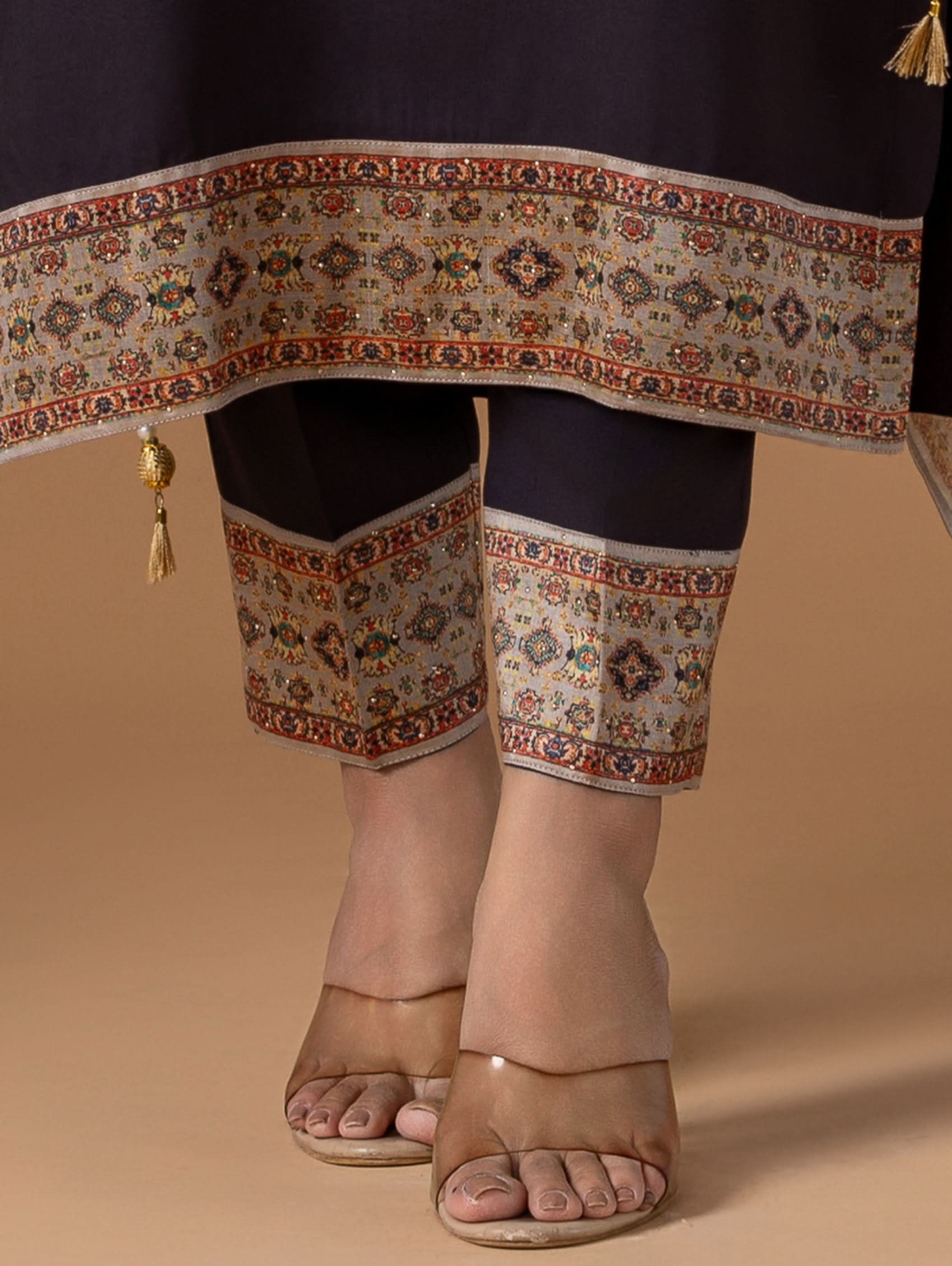 Traditional outfit with embroidered pants and a decorative belt on a beige background