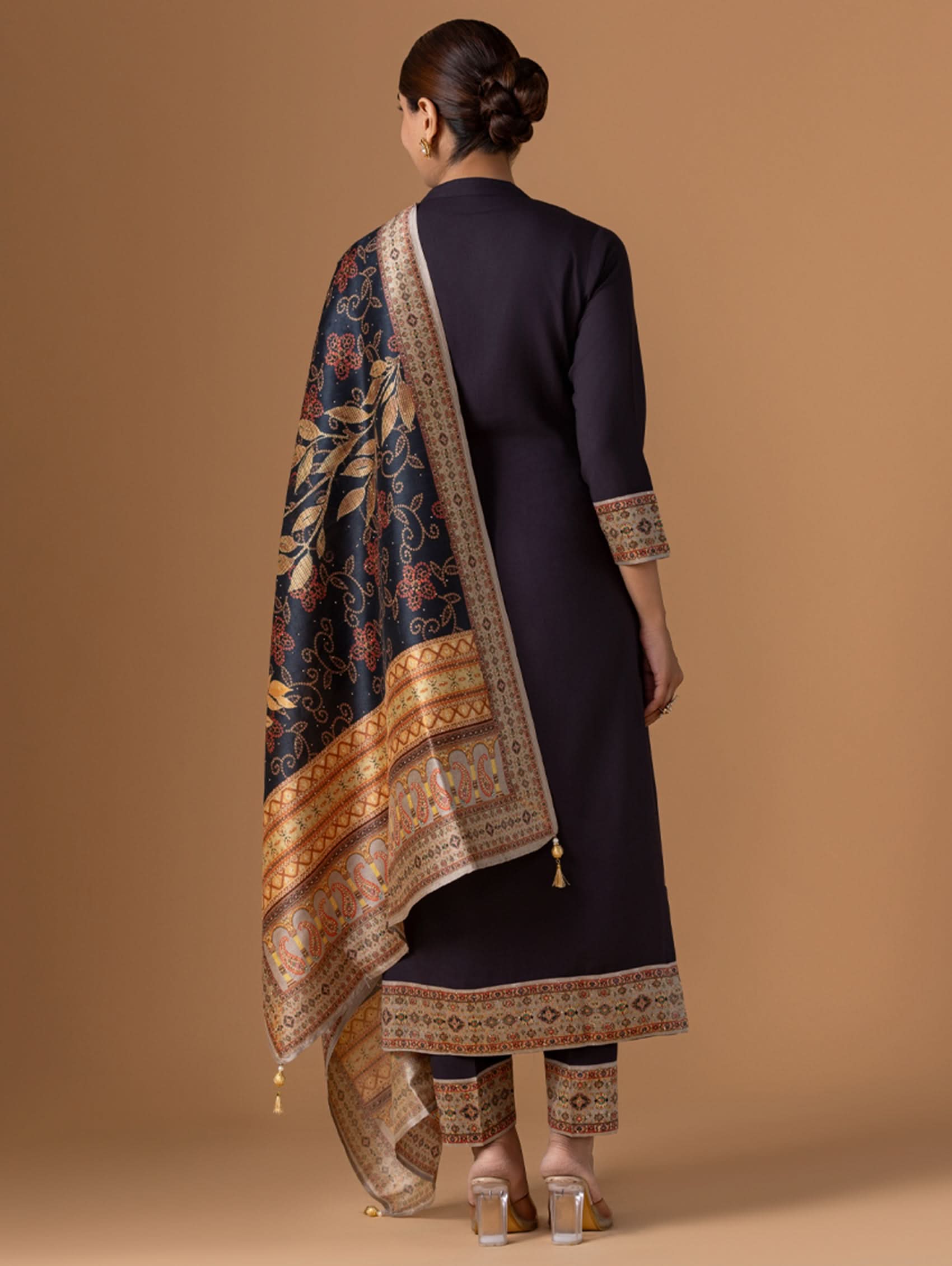 Woman wearing a dark blue traditional outfit with a patterned shawl on a brown background