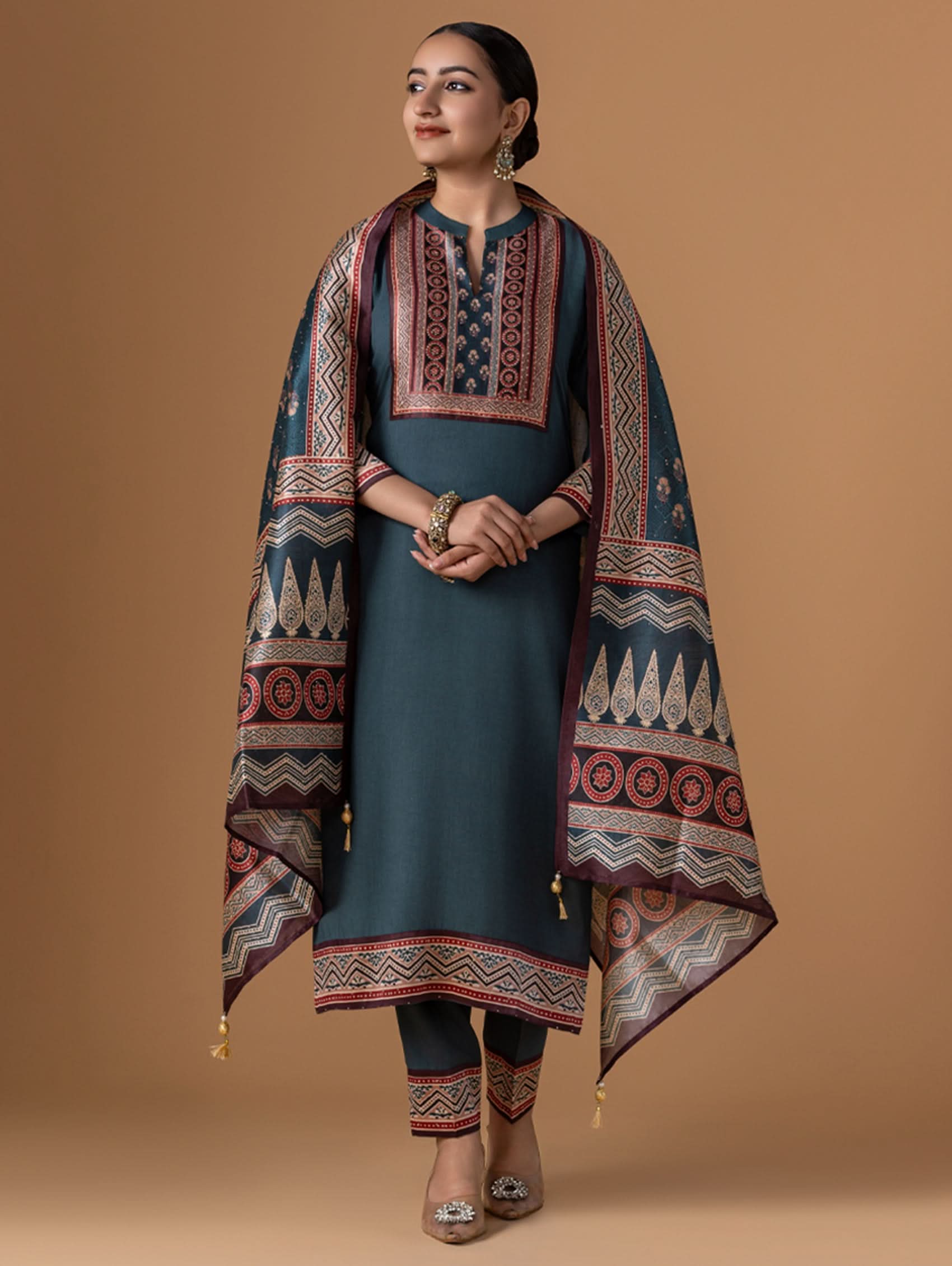 Woman wearing a dark blue dress with a patterned shawl against a brown background