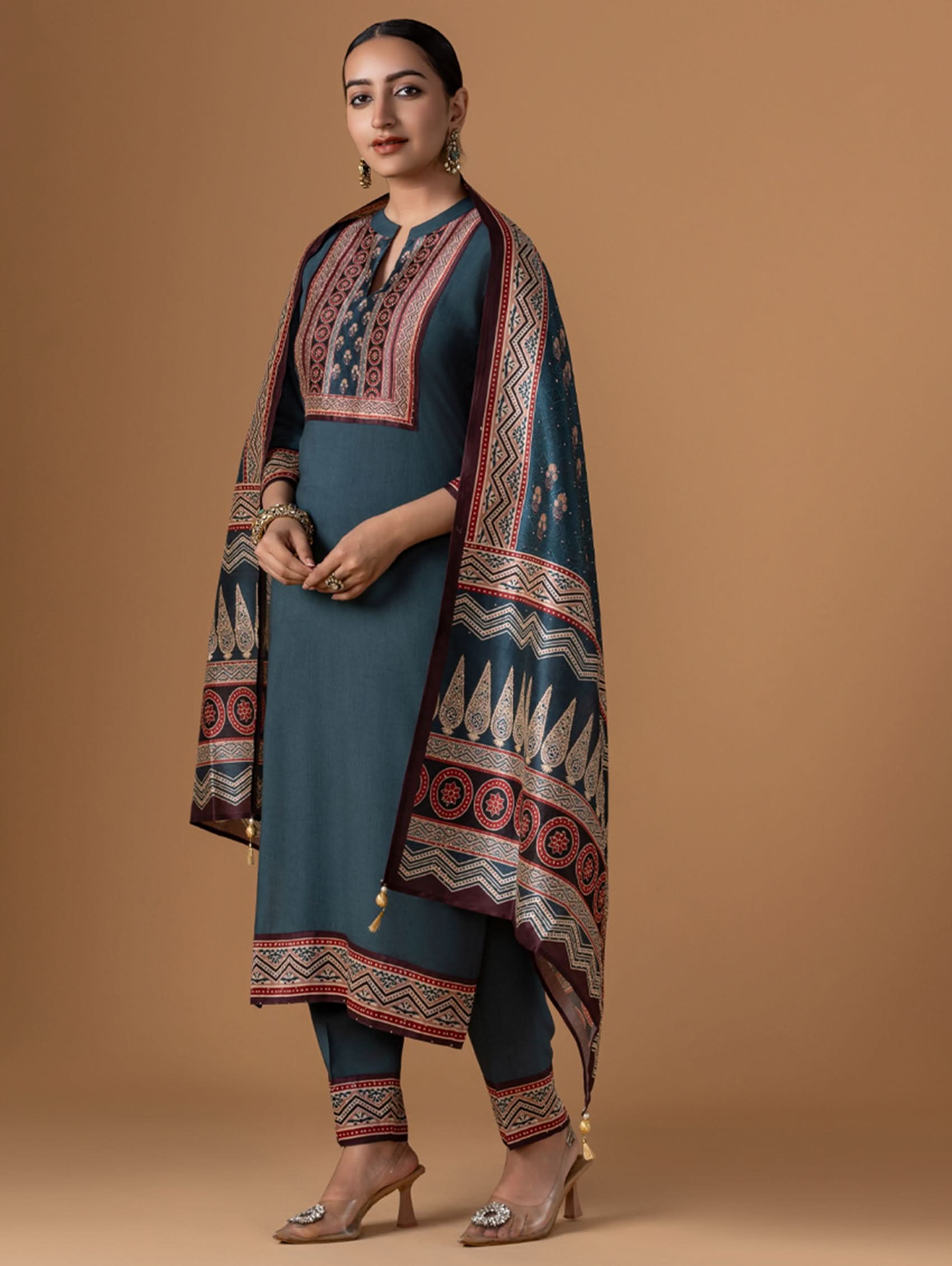 Woman wearing a traditional outfit with a patterned shawl on a brown background