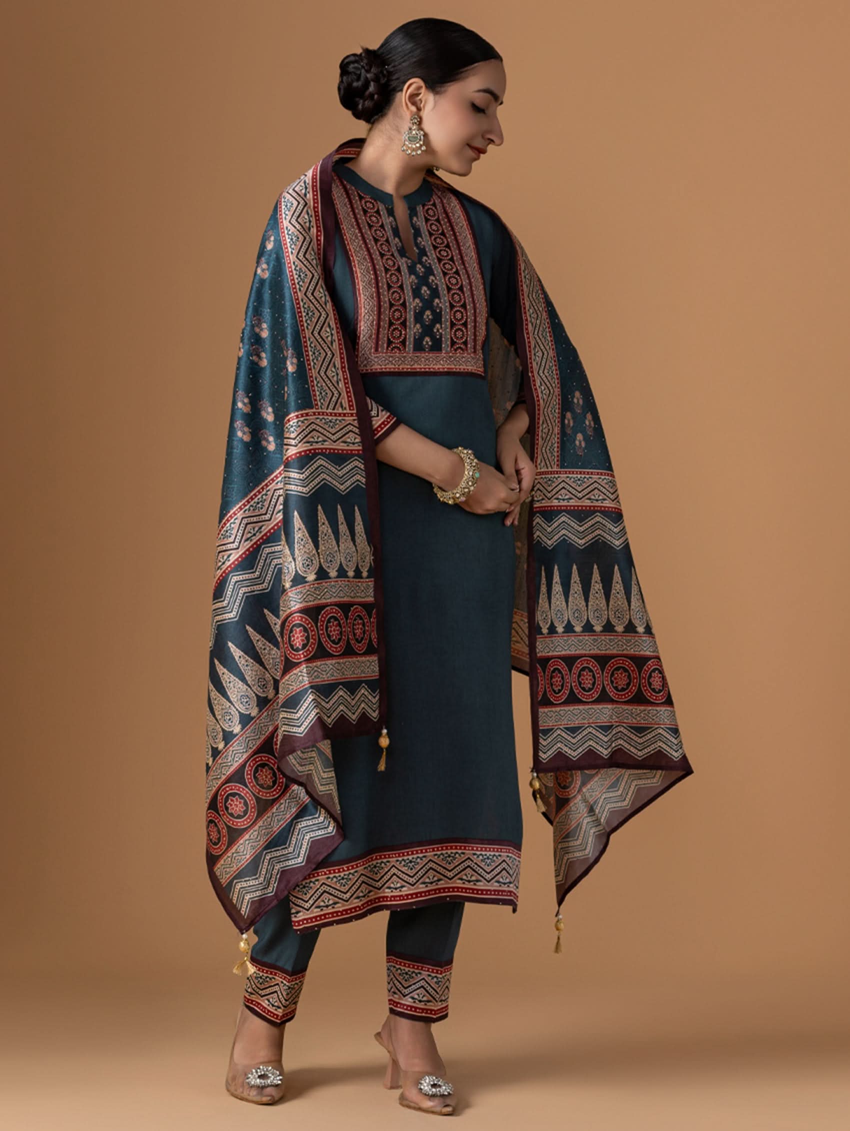 Woman wearing a traditional outfit with a patterned shawl against a brown background