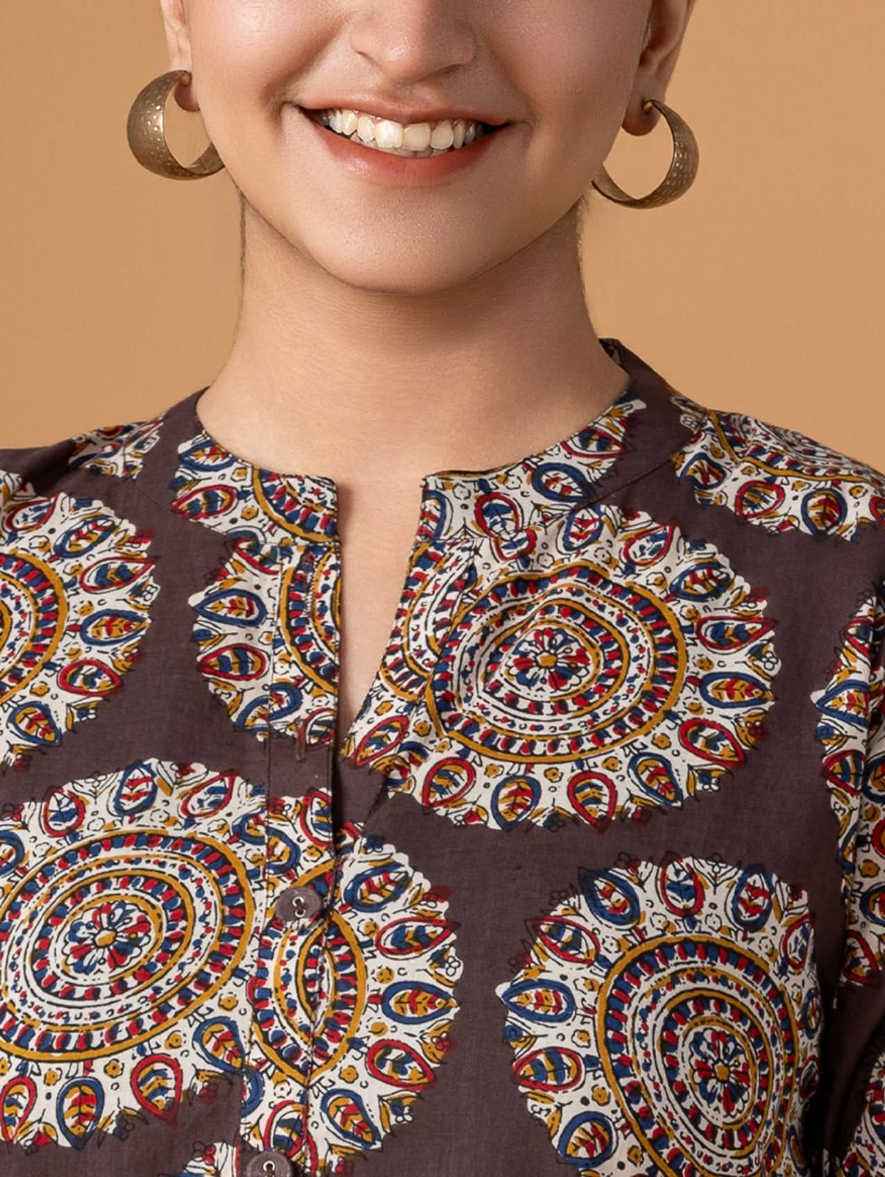 Woman wearing a brown top with colorful circular patterns on a beige background