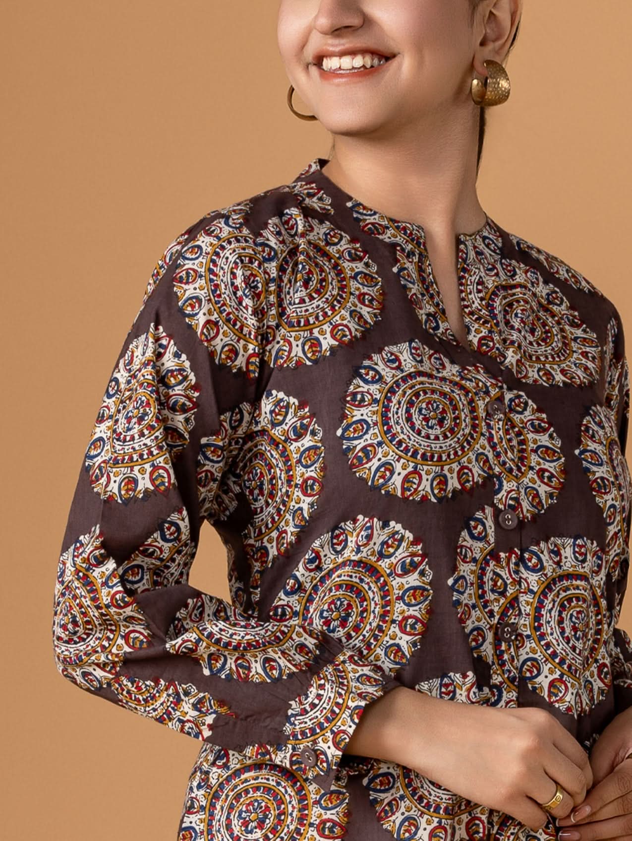 Woman wearing a patterned blouse against a brown background