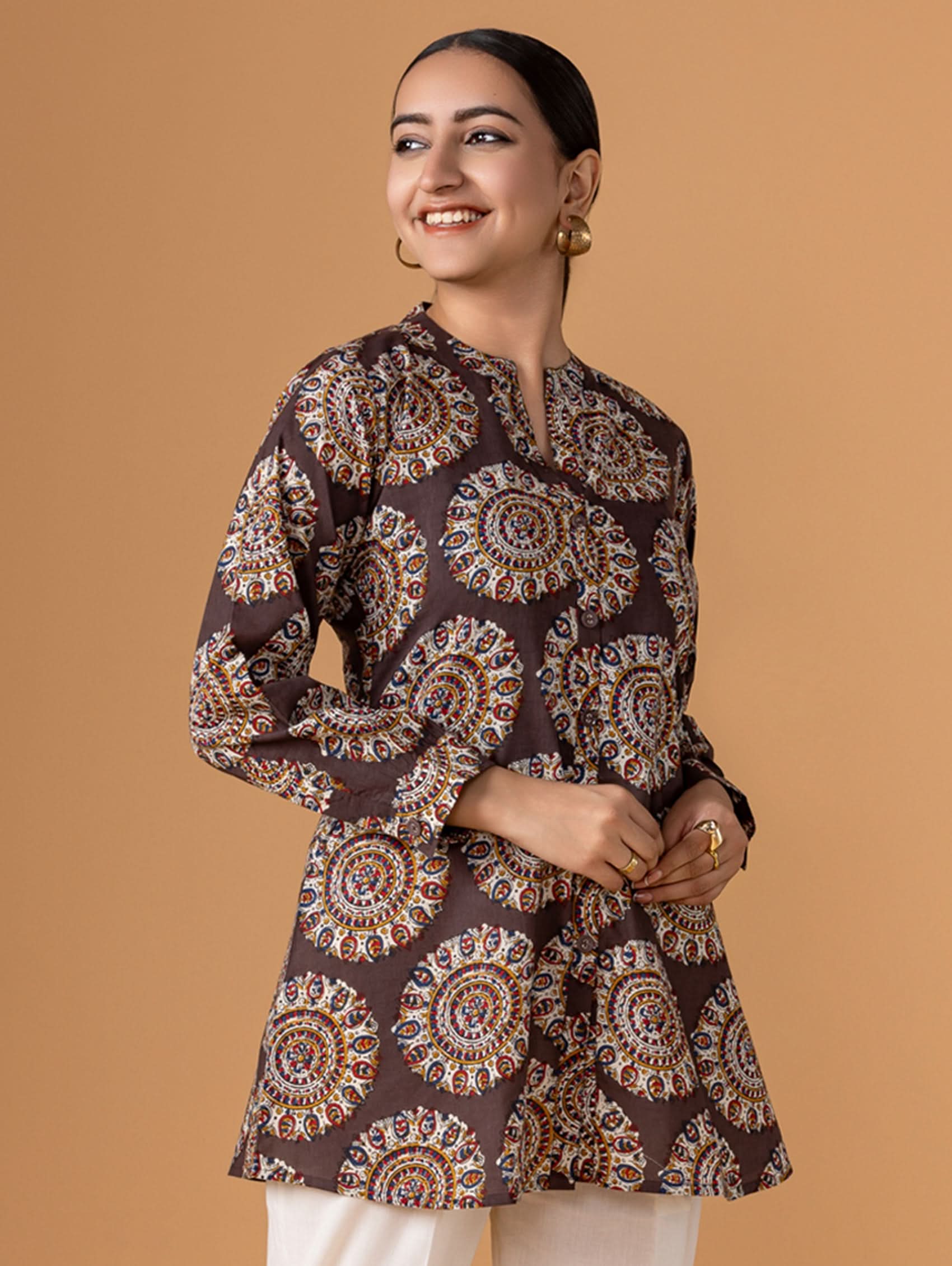 Woman wearing a patterned brown shirt against a beige background