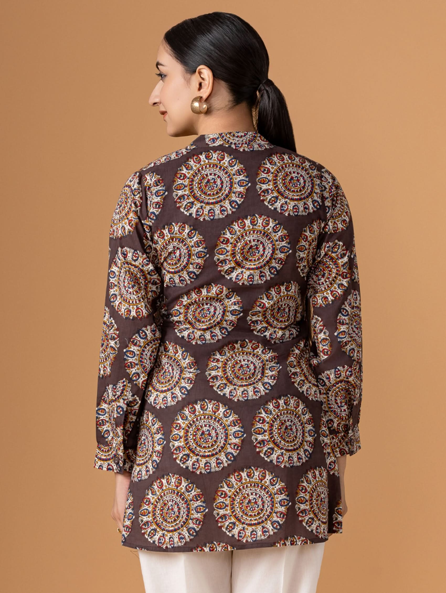 Woman wearing a brown patterned shirt against a beige background
